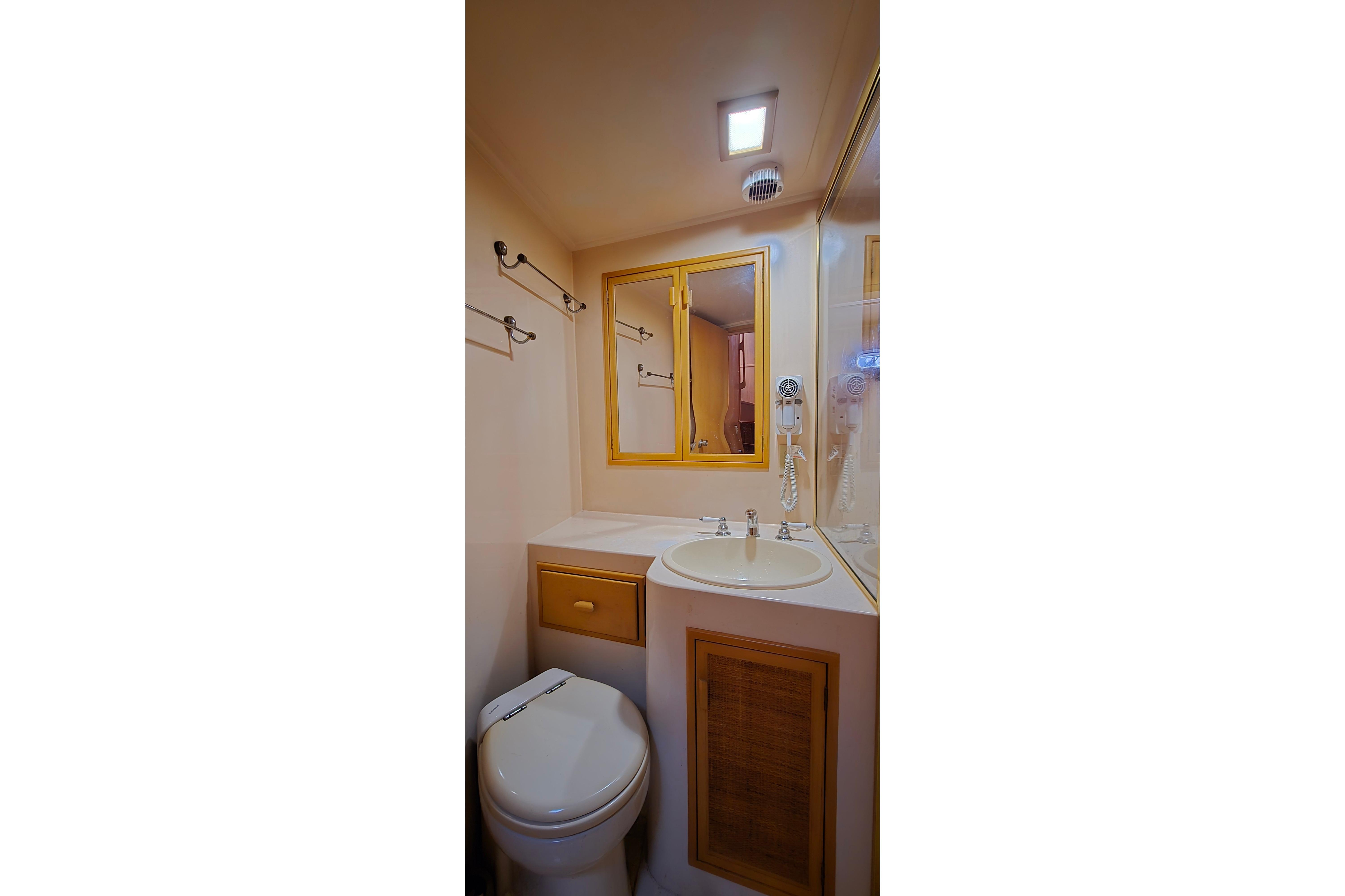 Compact bathroom in a 1987 Southern Cross 53 yacht, featuring sink, mirror, and toilet.