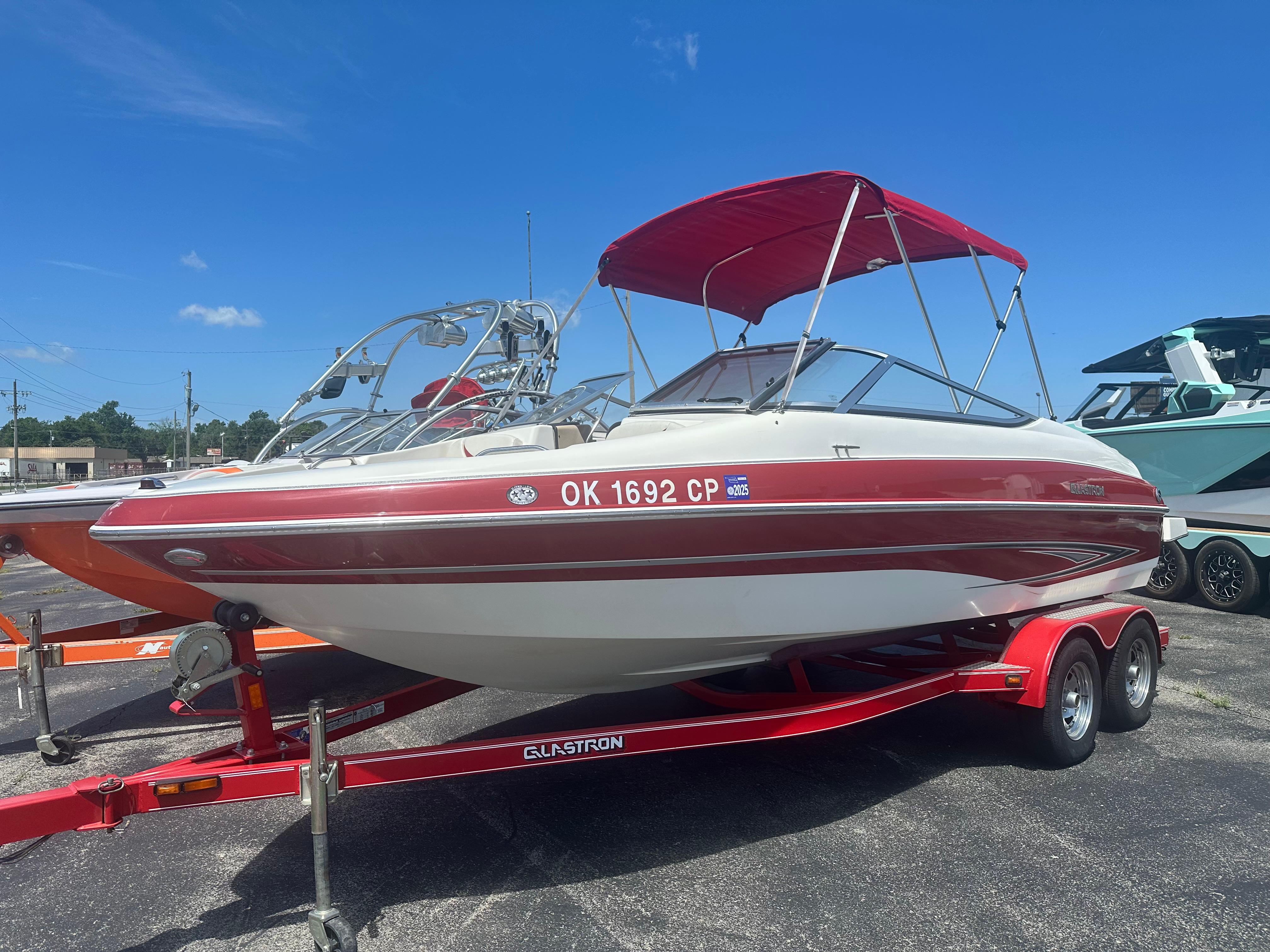 2008 Glastron 205 GX boat with red canopy on trailer, parked outdoors.