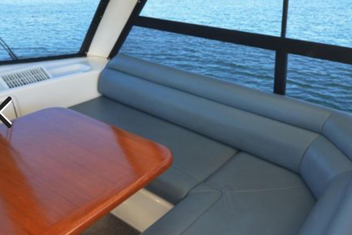 Interior of 2000 Riviera 48 Enclosed Flybridge with blue seating and wooden table.