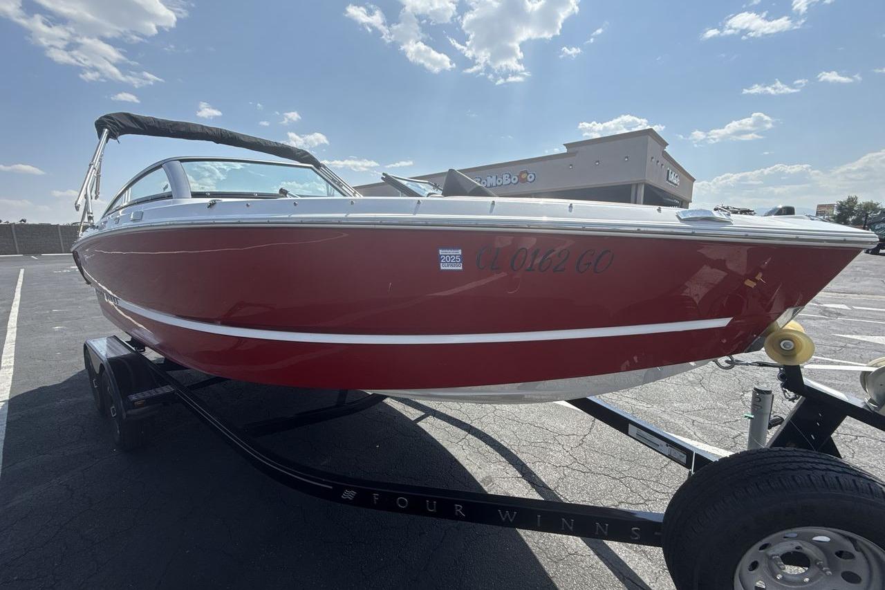2024 Four Winns H1 OB boat in red on a trailer, parked outdoors.
