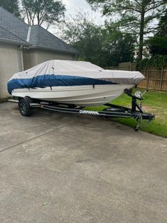 A 2004 Chaparral 190 SSi boat on a trailer in a driveway, covered with a tarp.