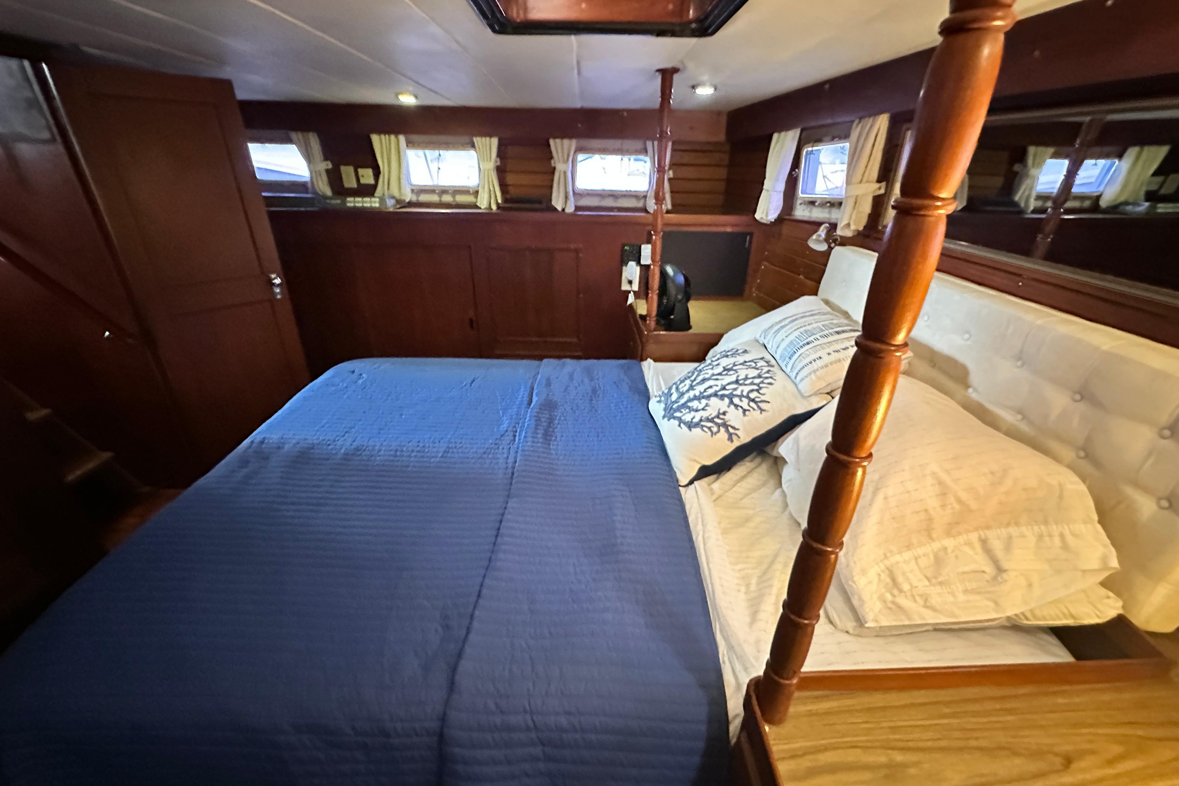 Cozy bedroom in 1980 Island Gypsy Flush Aft Deck Trawler-Motor Yacht with blue bedding.