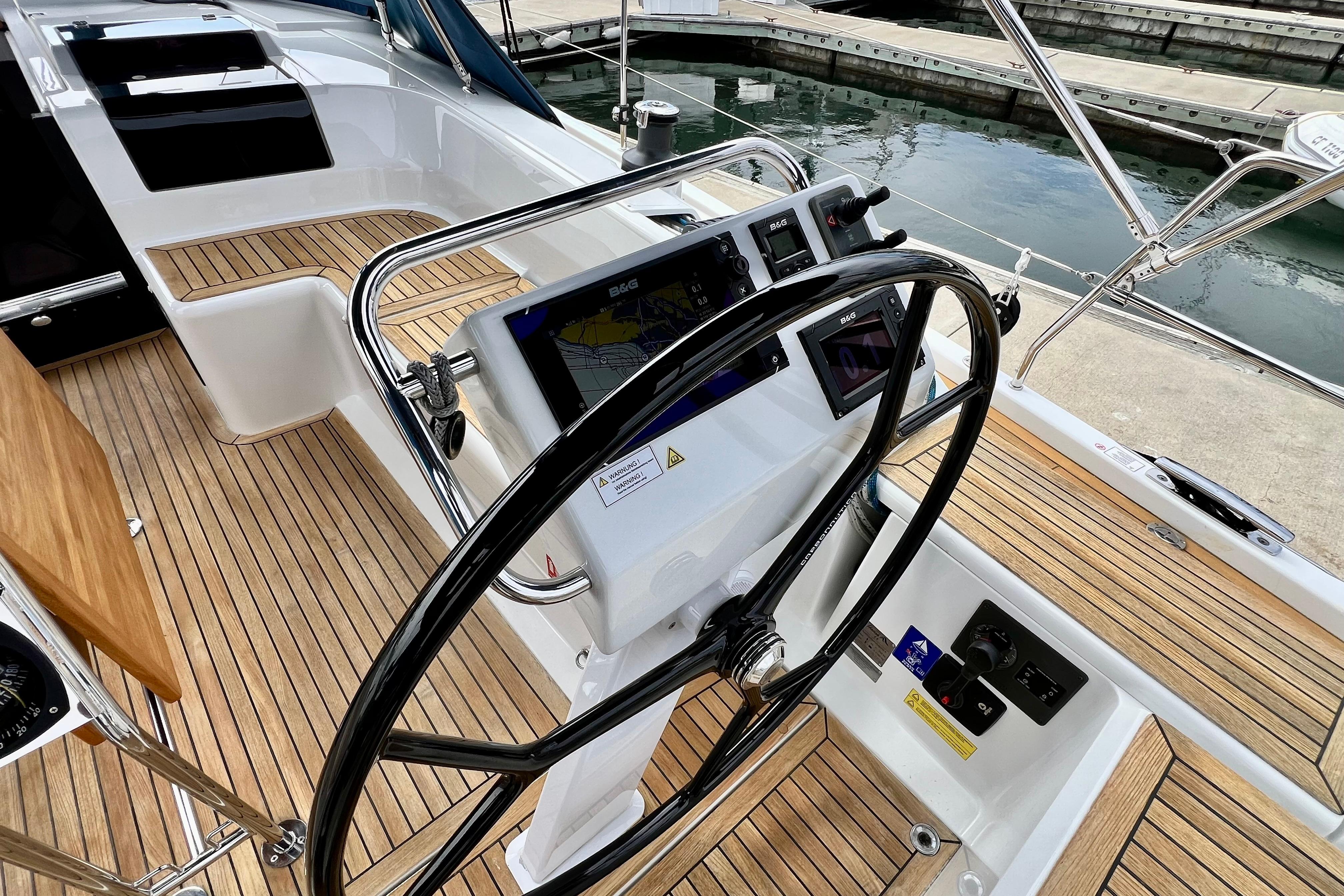 Steering wheel and navigation system on 2016 Hanse 455 yacht, docked at marina.