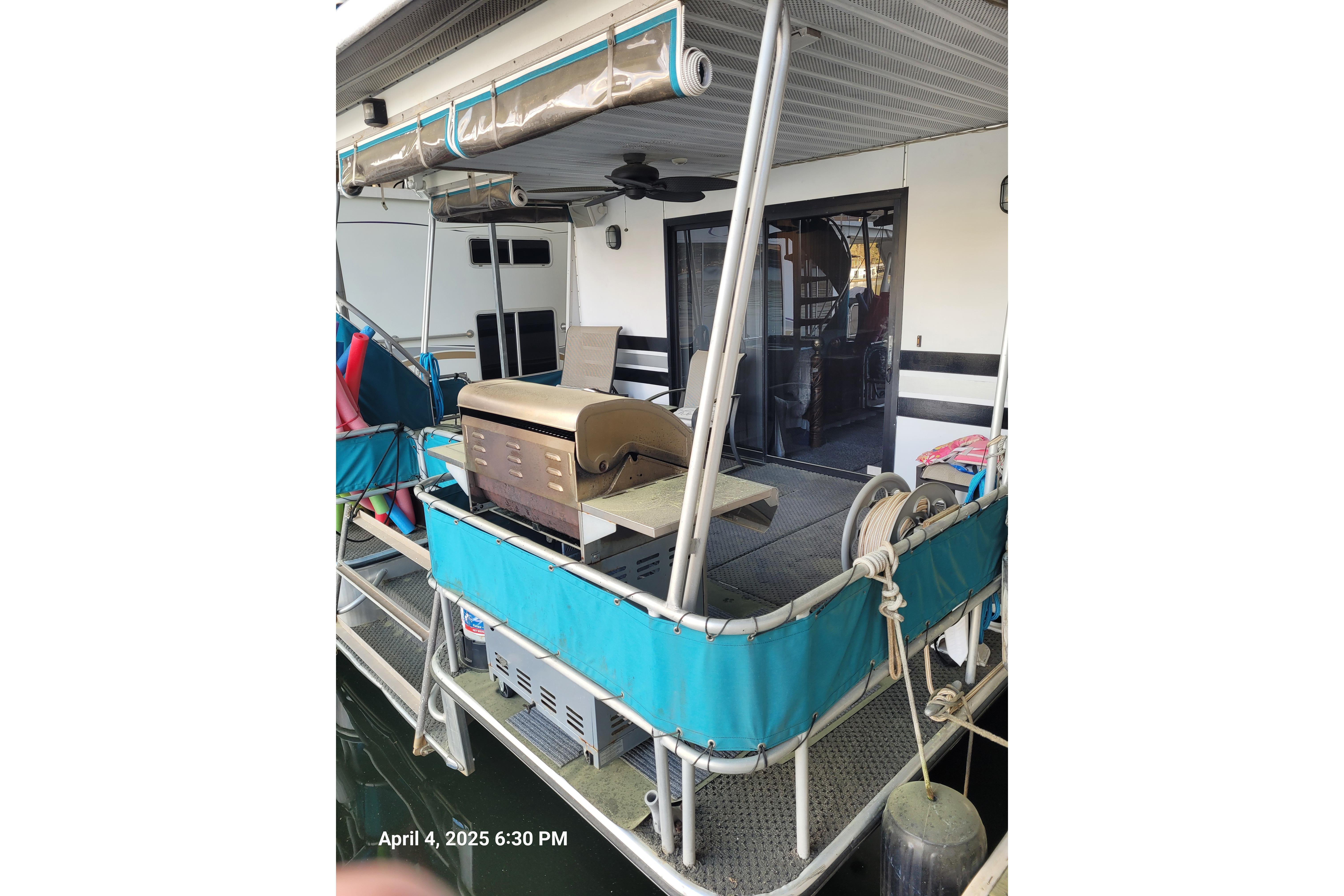 Houseboat deck with grill, blue awning, and seating on a 1990 Sumerset 16 x 70 model.