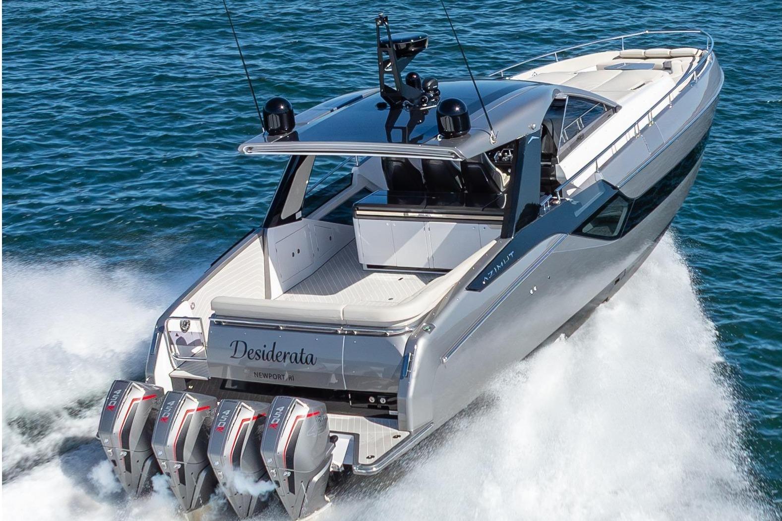A luxury motorboat with four outboard engines speeding across the water.