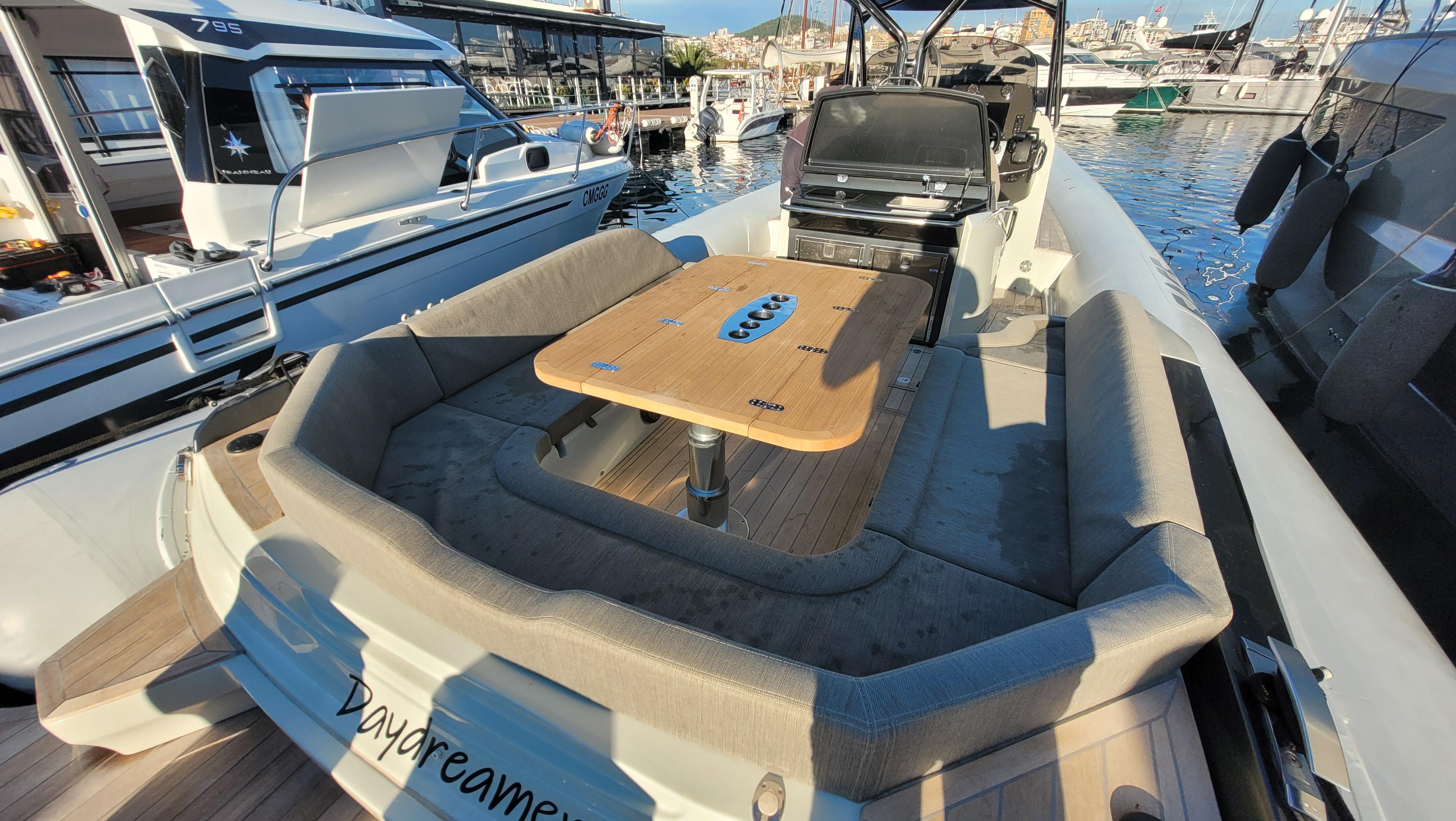 SACS Strider 11, 2022, luxury boat with seating area and table in harbor.