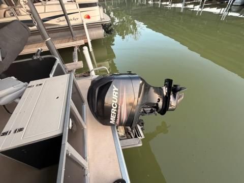 A Mercury outboard motor is attached to a boat docked in a calm marina.