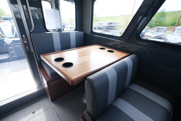 Interior of 2024 Hewescraft 250 Explorer with dining table and striped seating.