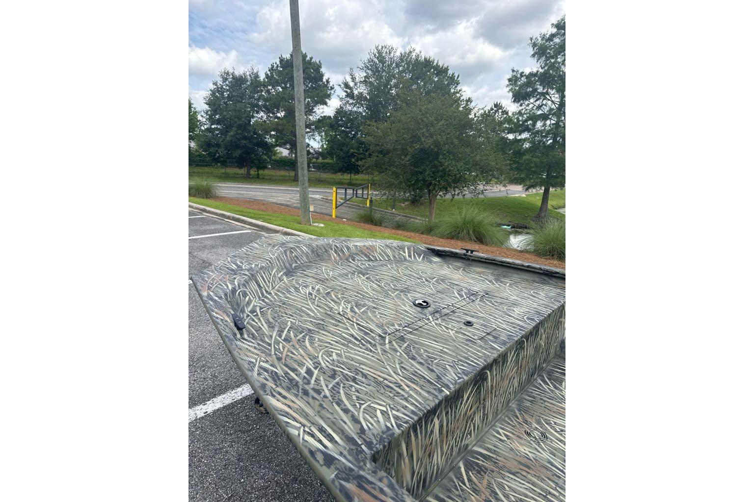 2026 Tracker Grizzly 1648 Utility boat with camouflage design in a parking lot.