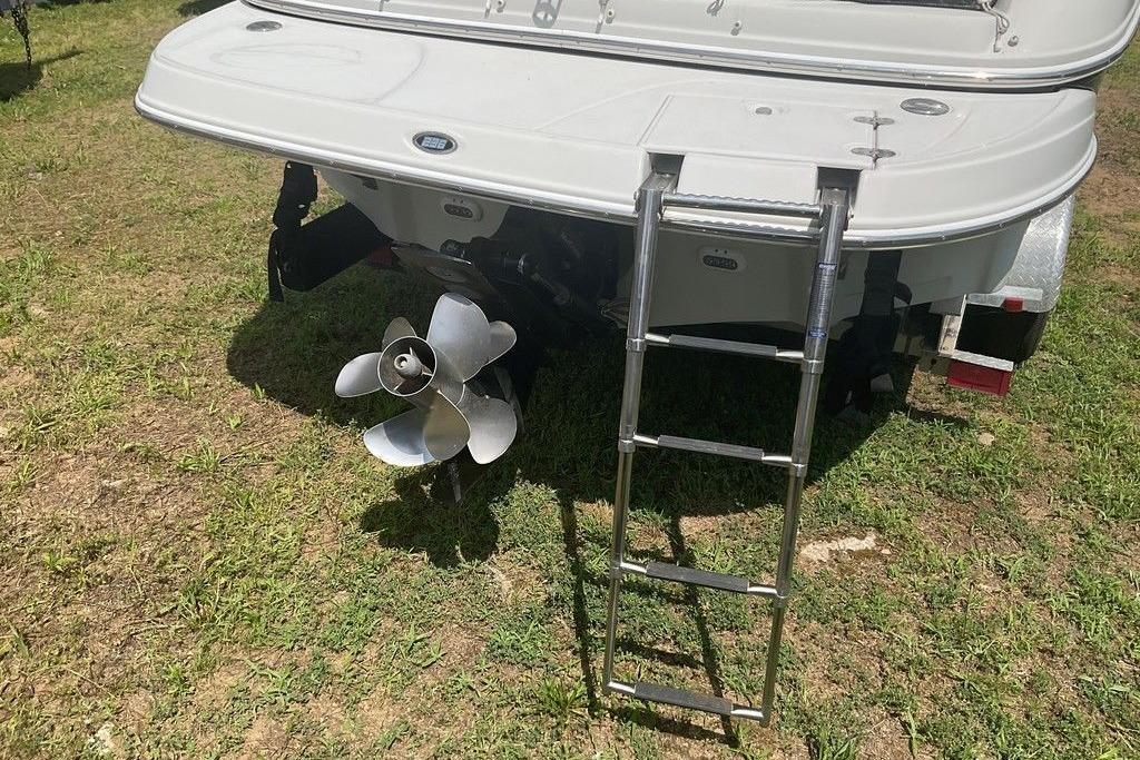 Rear view of 2015 Crownline 236 SC boat with ladder and propeller on grass.