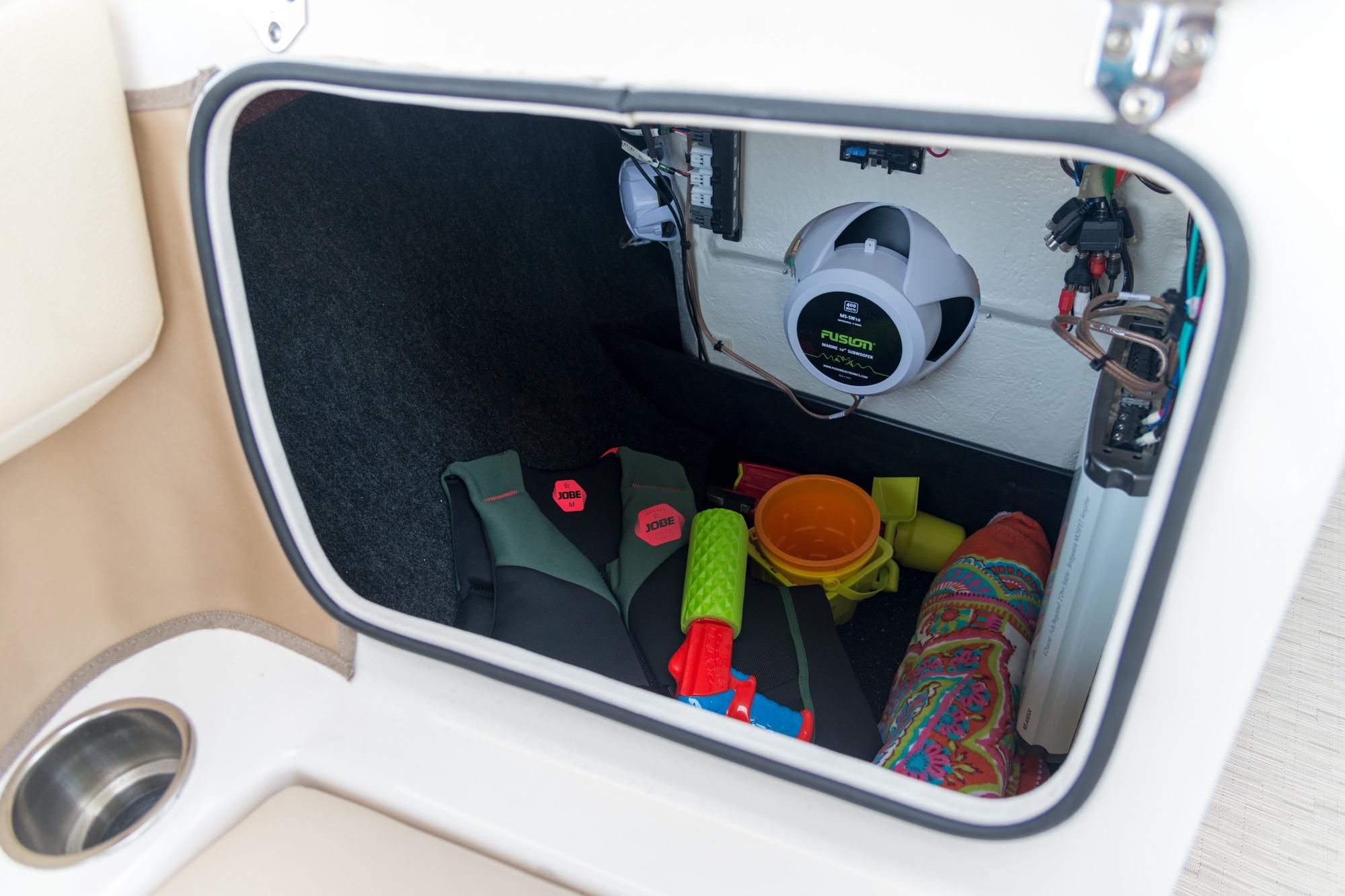 Storage compartment of 2026 Regal 21 OBX boat with life vests and toys.