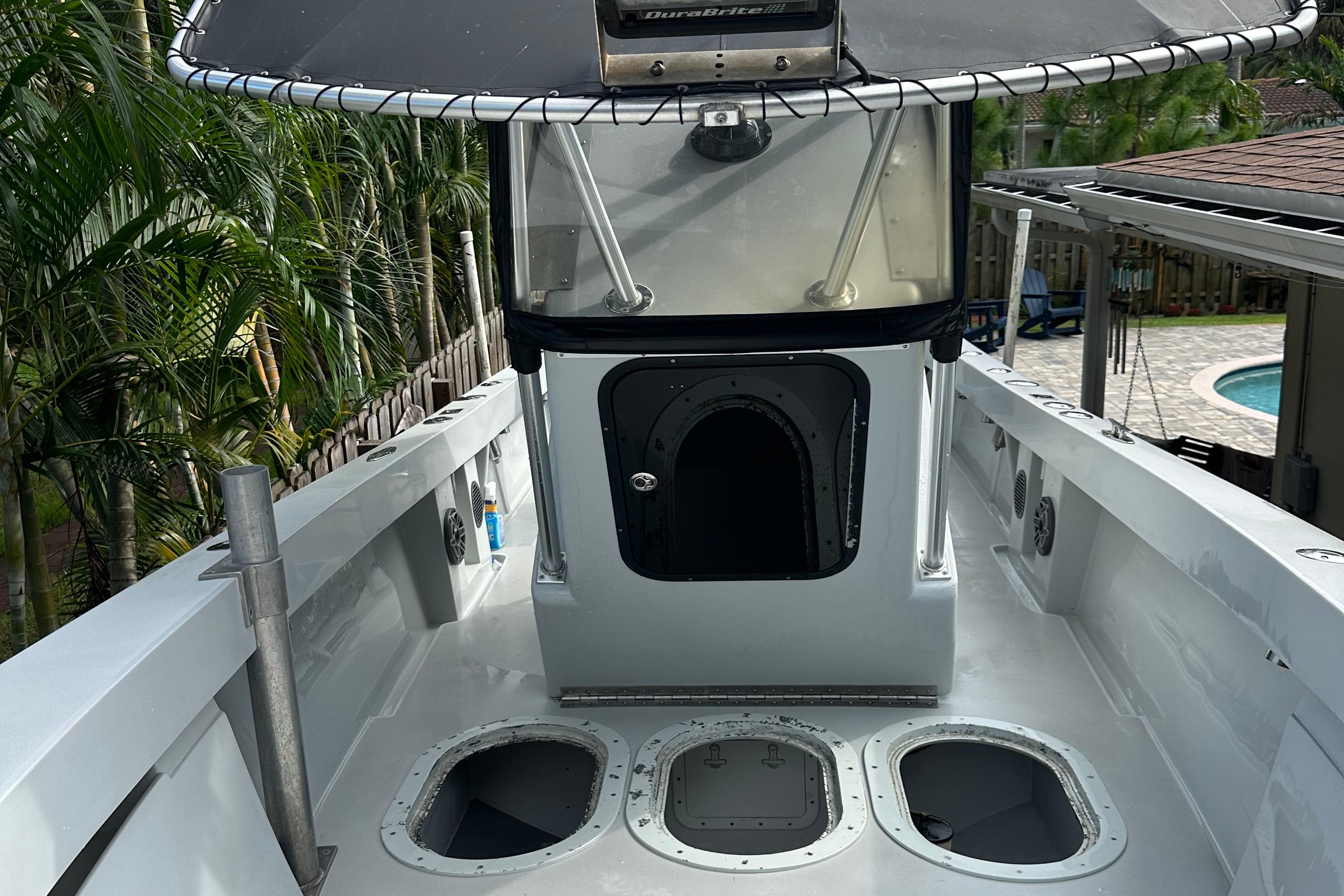 2004 SeaVee Center Console boat with T-top, docked near tropical foliage.