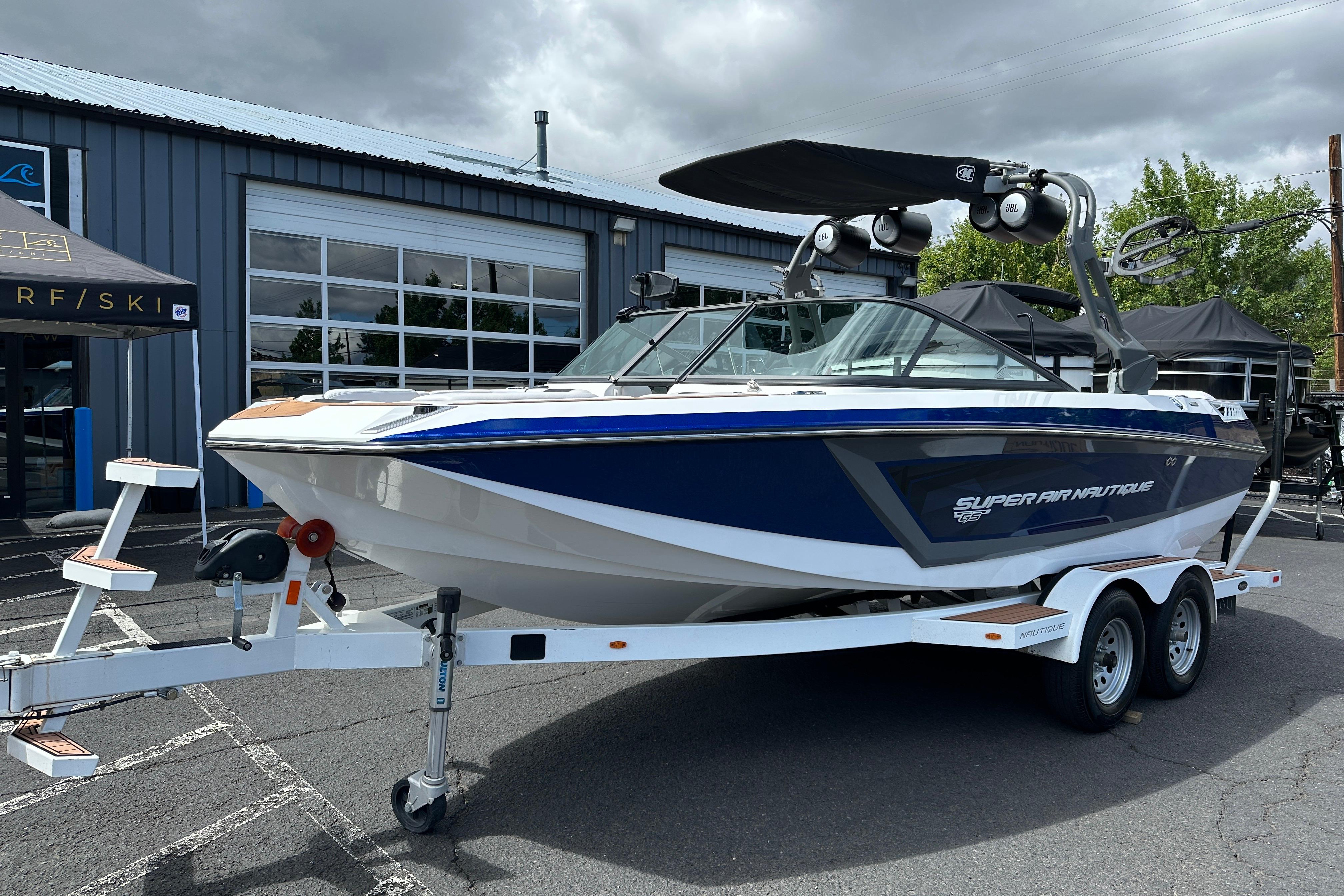 2017 Nautique Super Air Nautique GS20 boat on trailer, parked outside a building.