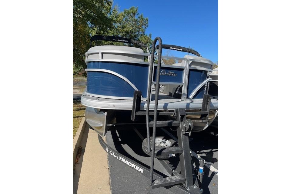 2026 Sun Tracker SportFish 22 DLX pontoon boat on trailer, parked outdoors.