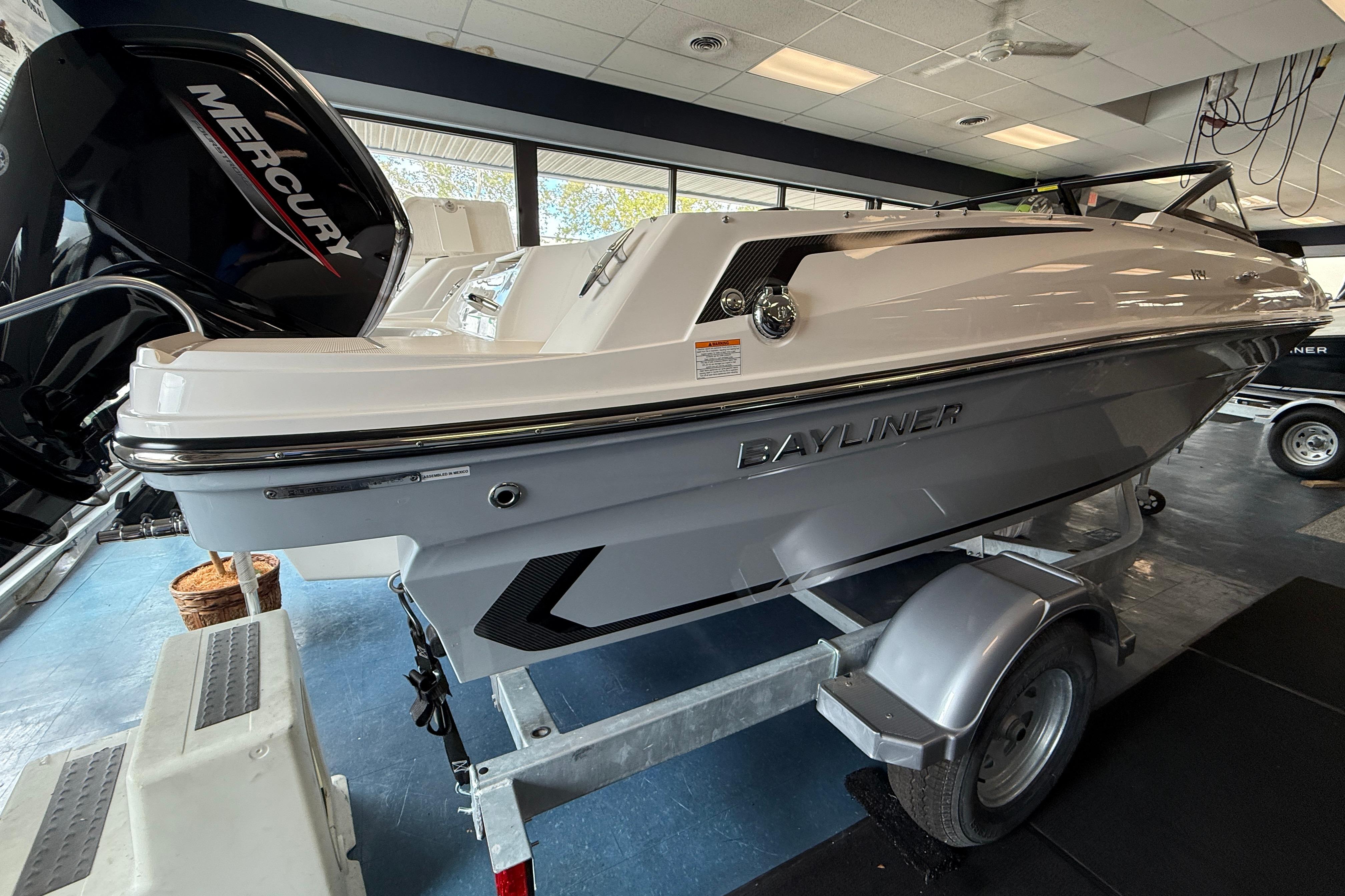 2025 Bayliner VR4 Bowrider OB on trailer in showroom, featuring Mercury outboard engine.