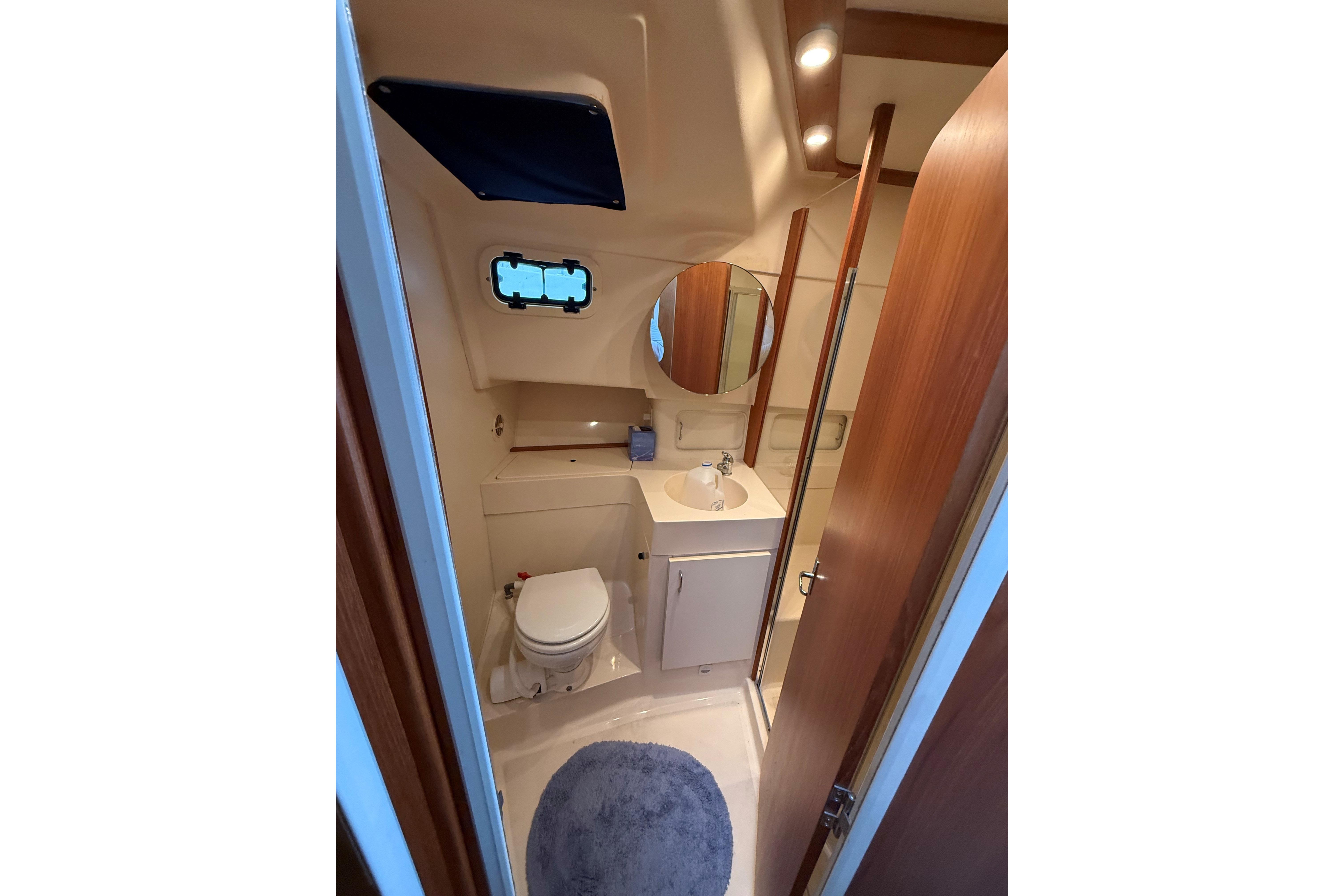 Bathroom interior of 1999 Mainship 350 Trawler with sink, toilet, and mirror.