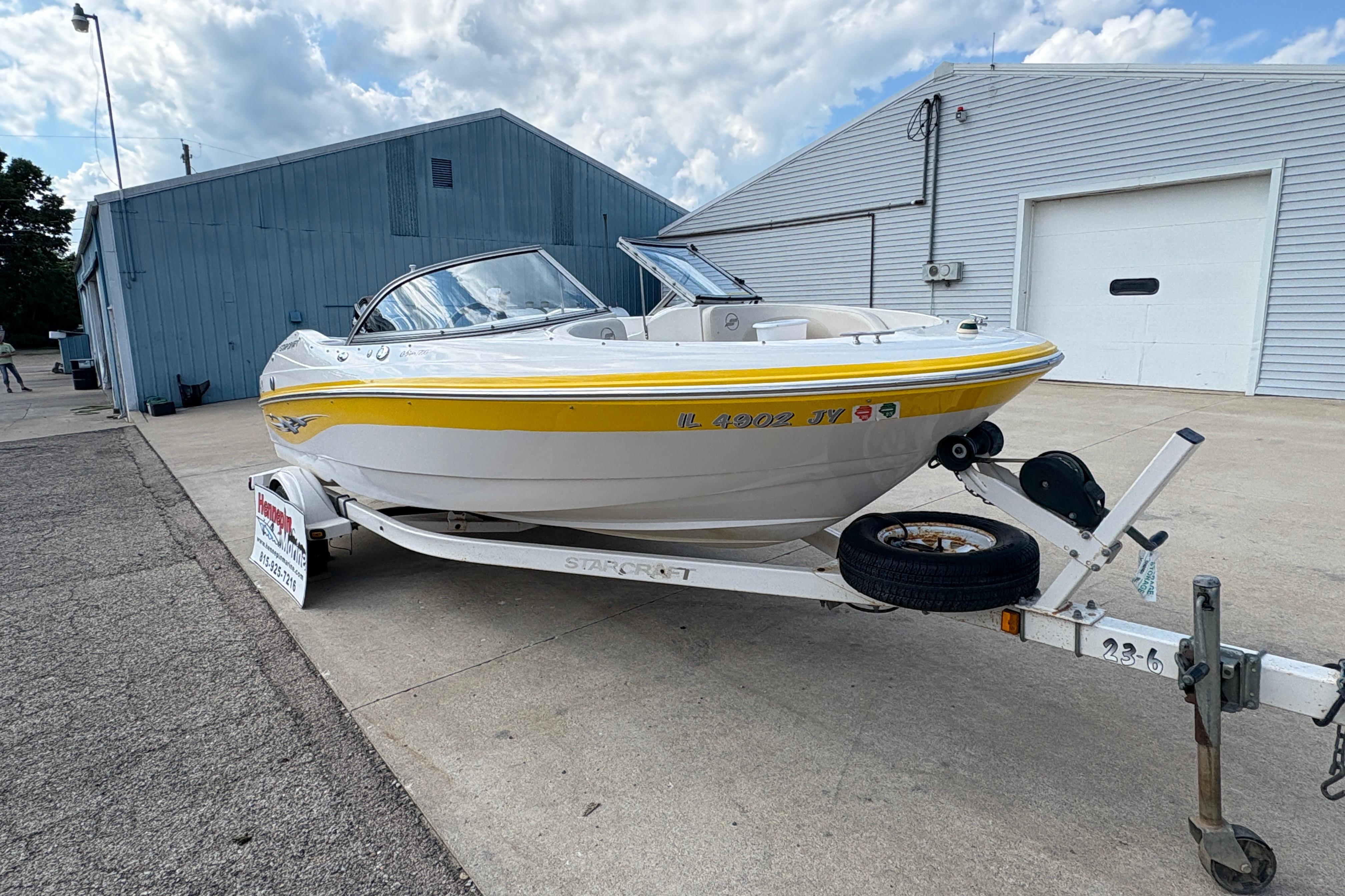 2005 Starcraft C-Star 1700 OB boat on trailer, parked outside a blue building.