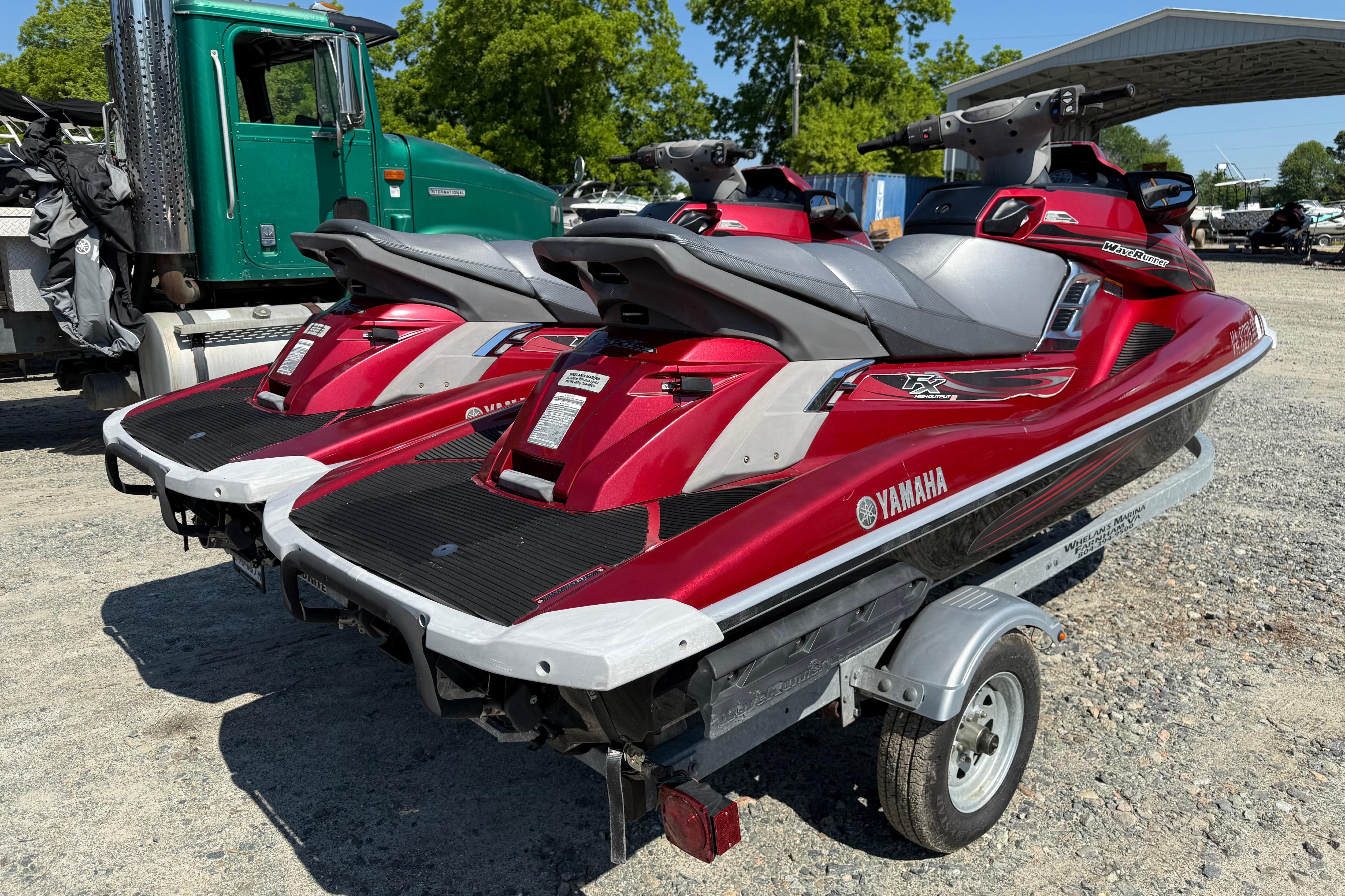 Red 2013 Yamaha WaveRunner FX HO jet skis on a trailer, parked outdoors.