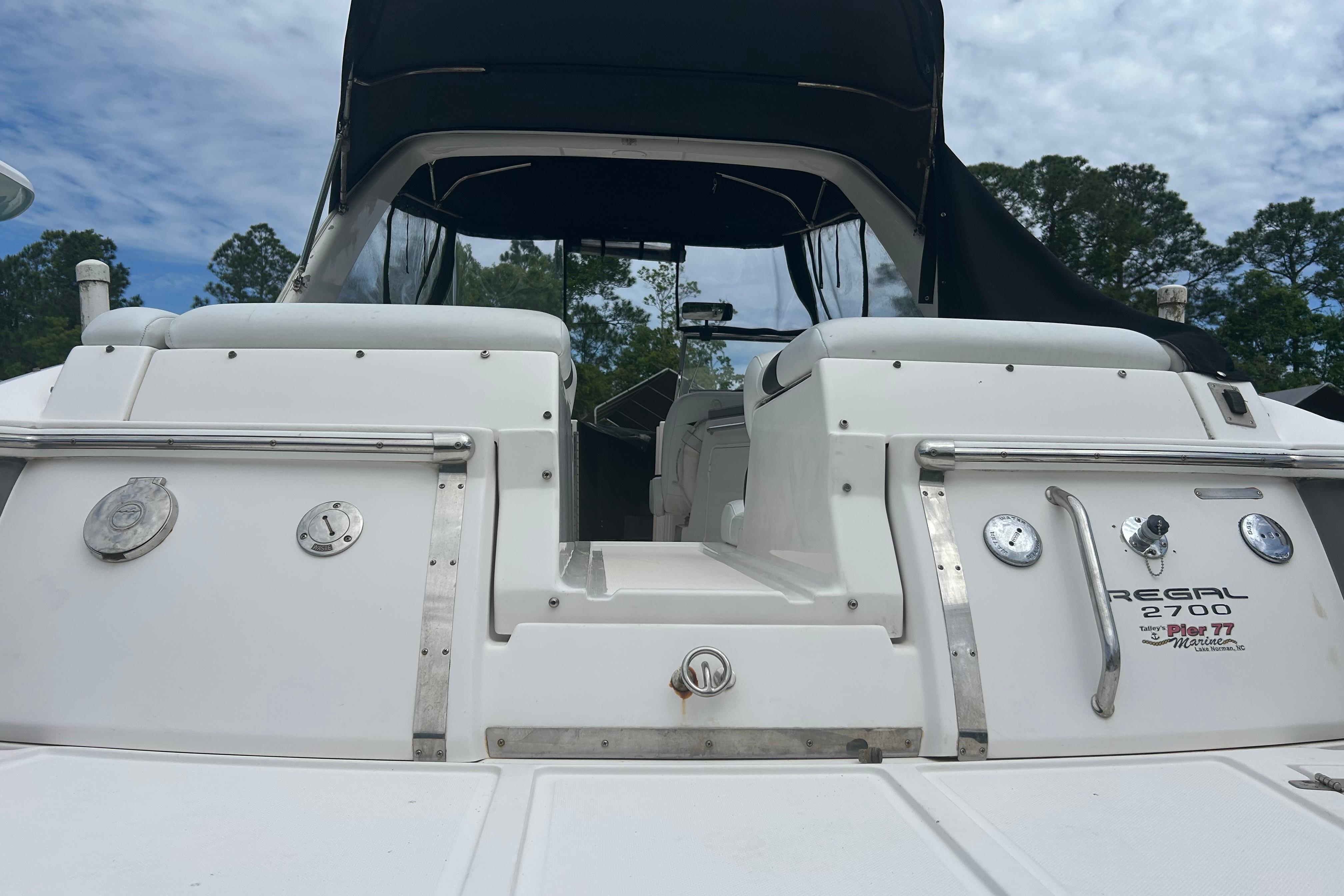 2008 Regal 2700 Bowrider boat with white exterior and black canopy, docked outdoors.
