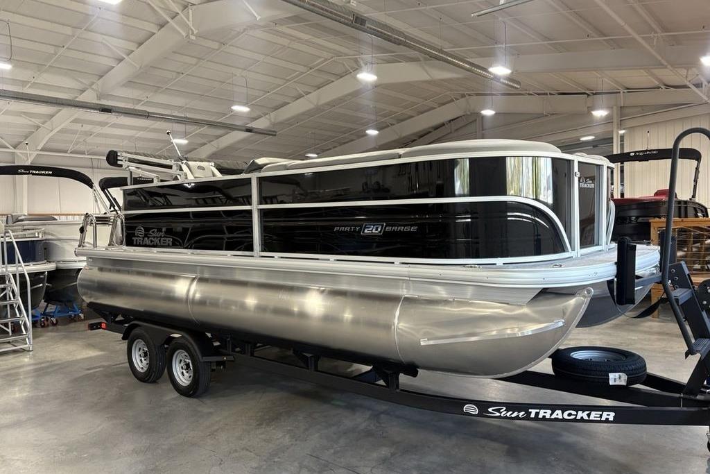 2026 Sun Tracker PARTY BARGE® 20 DLX pontoon boat in a showroom on a trailer.