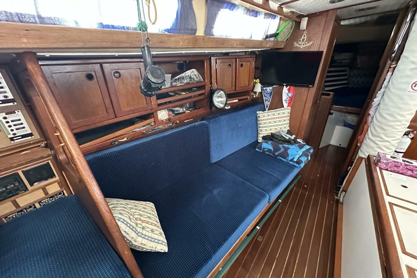 Interior of a 1979 Hughes 3910 sailboat with blue seating and wooden cabinetry.