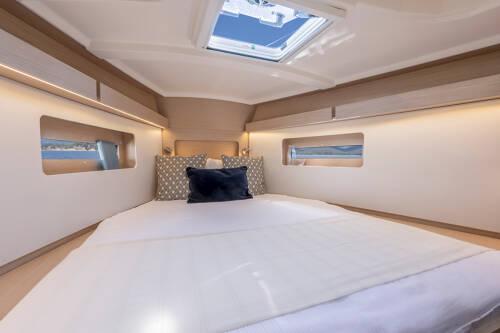 Luxurious cabin interior of 2025 Beneteau Oceanis 37.1 yacht with skylight and cozy bedding.