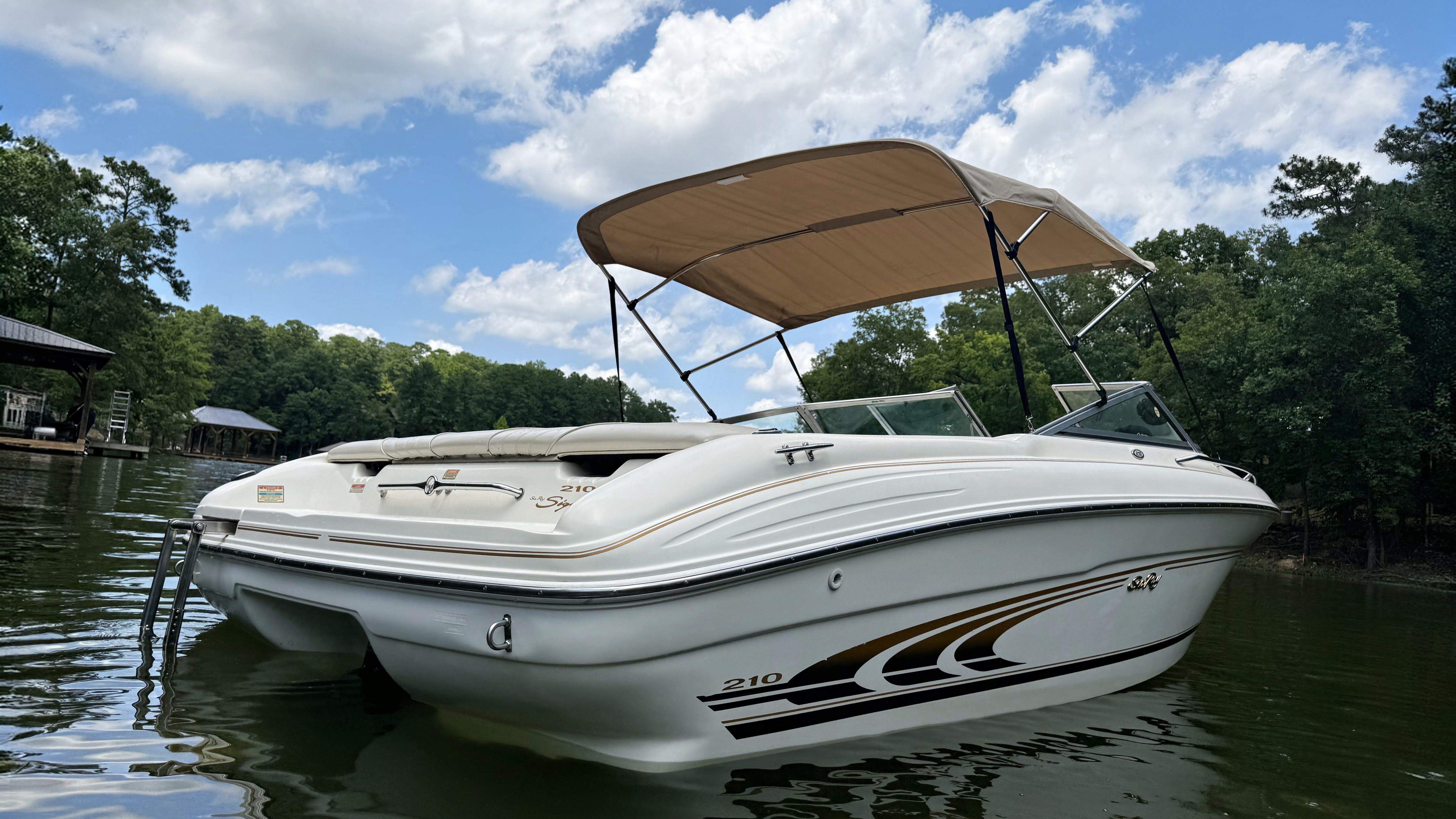 A white 1999 Sea Ray 210 Bow Rider Signature boat floats on a calm lake.