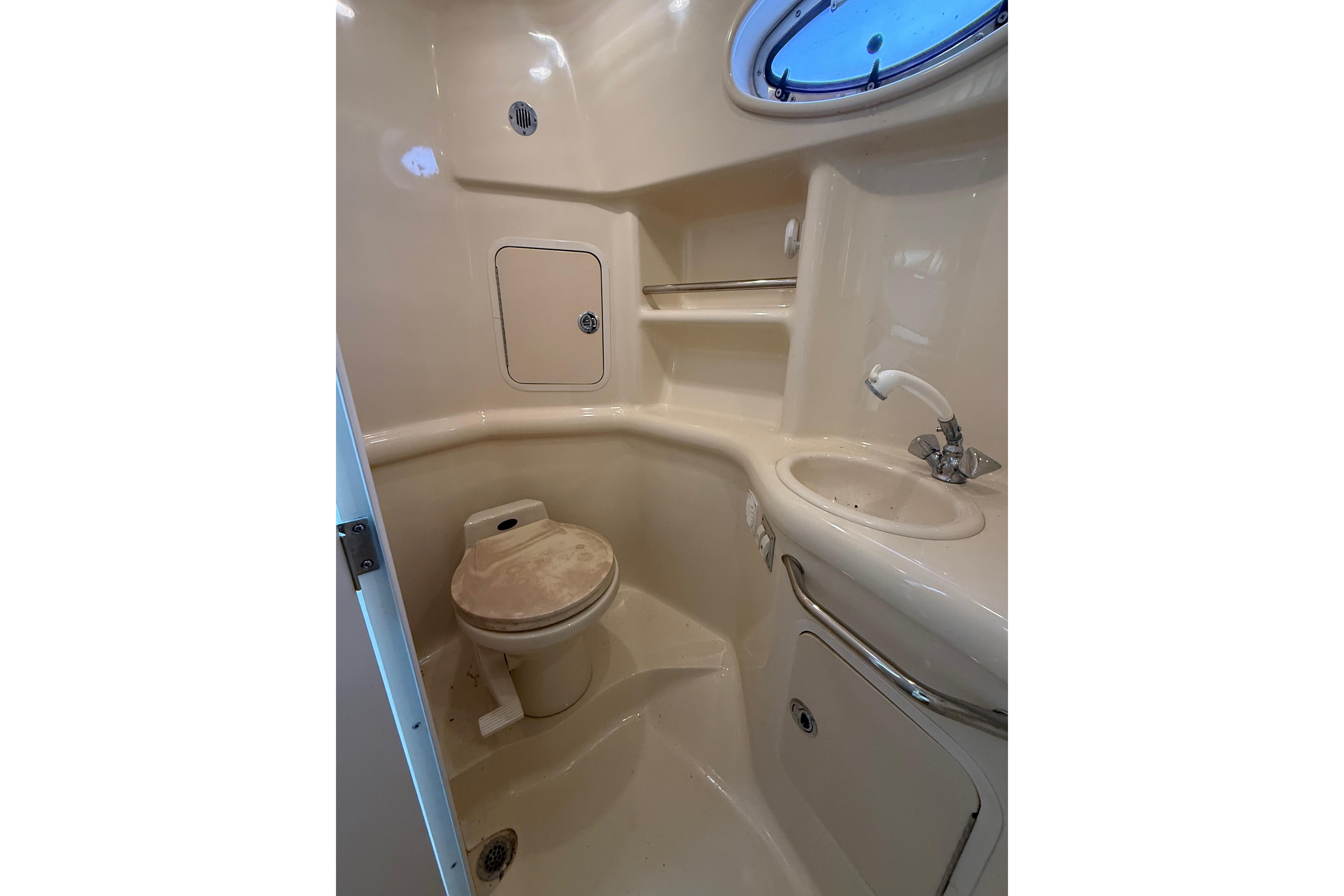 1999 Sea Ray Sundancer 310 bathroom with toilet, sink, and storage compartments.