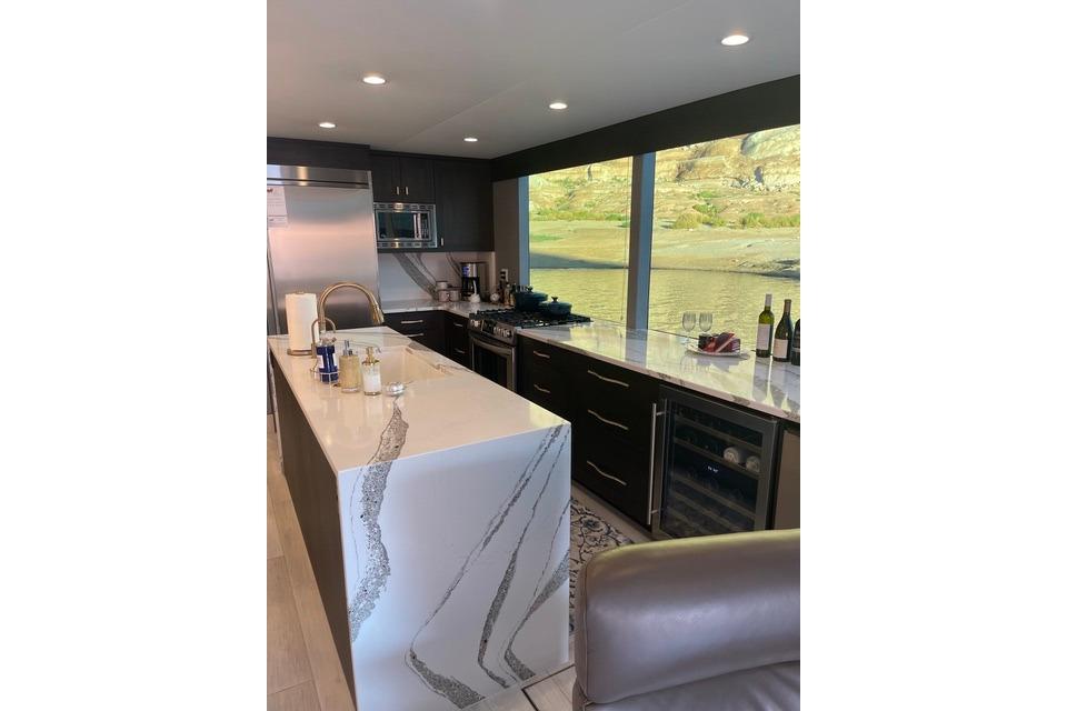 Modern kitchen interior on Adonia's 2021 "The Queen Elizabeth" with sleek countertops and scenic window view.