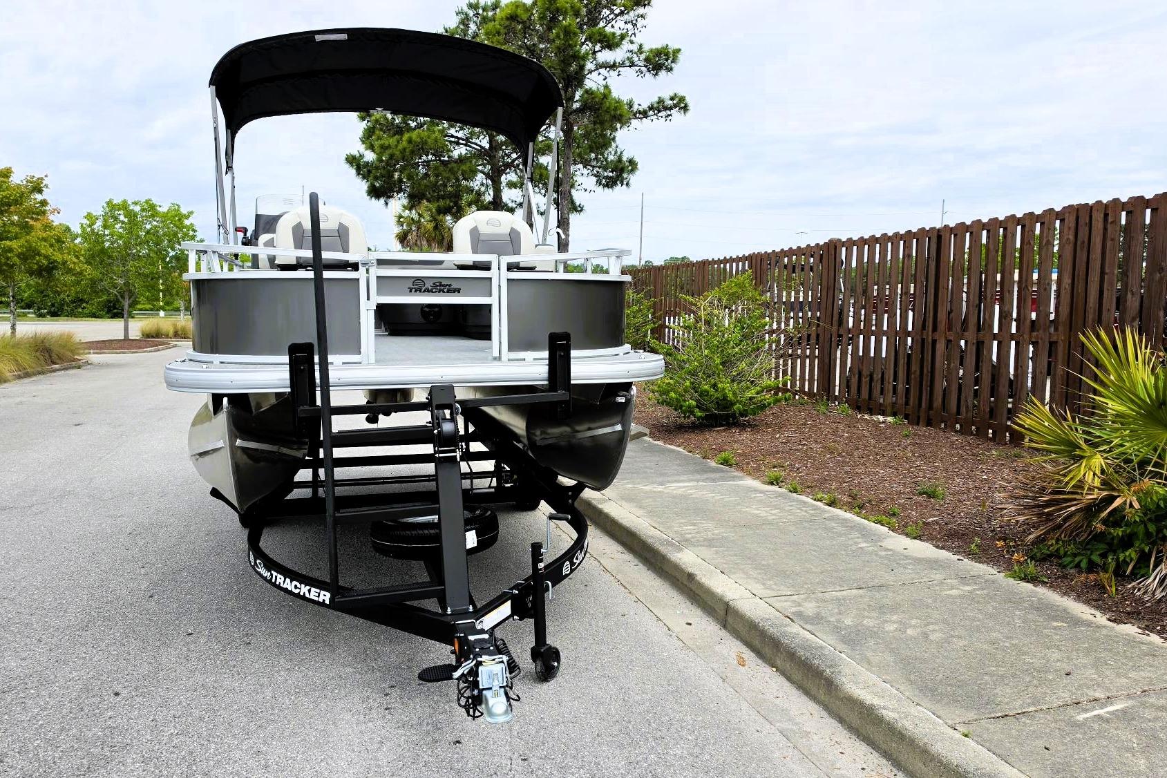 2026 Sun Tracker Bass Buggy 16 XL Select pontoon boat on trailer, parked roadside.