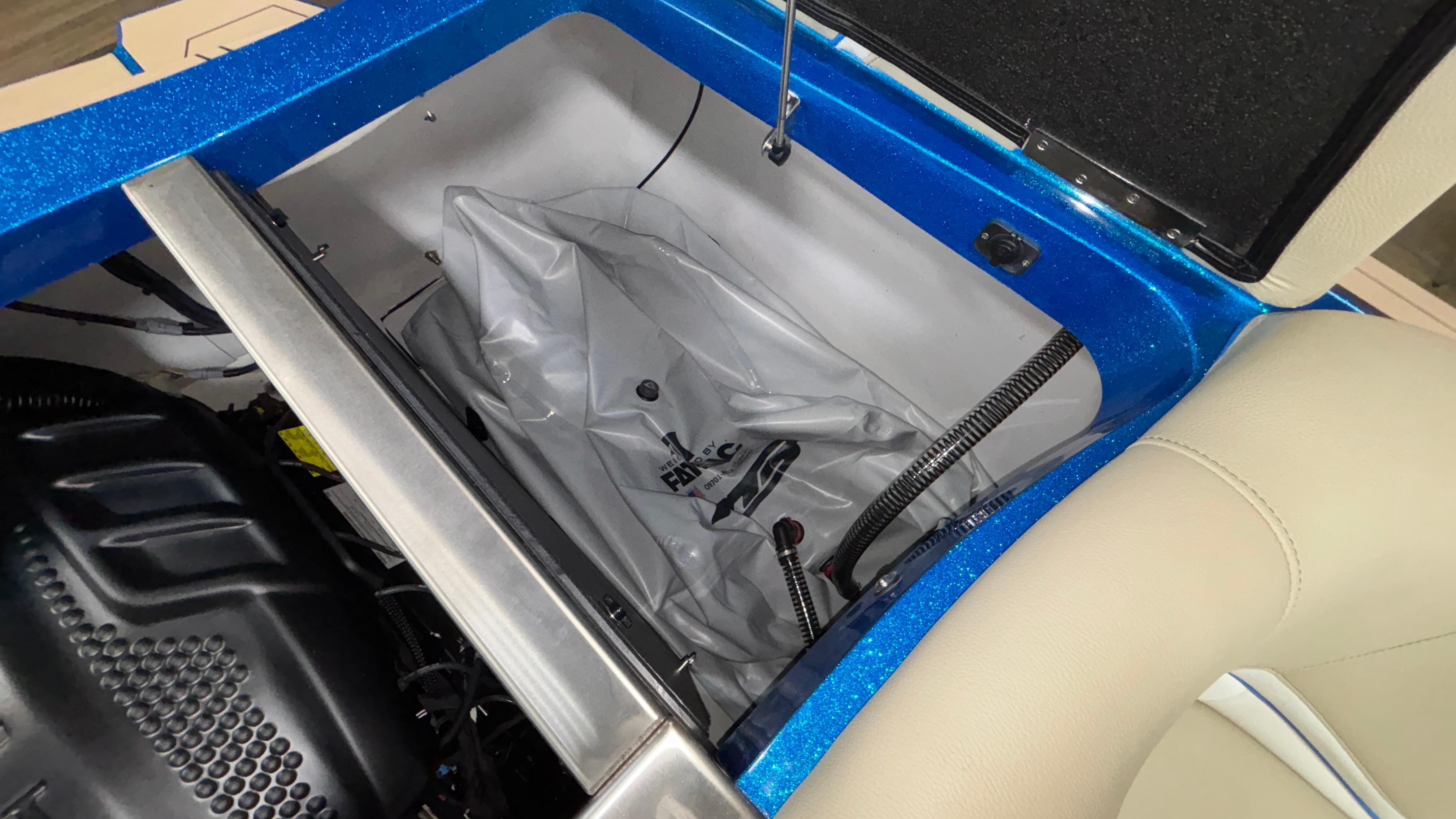 Open storage compartment in 2025 MB B52 23 Classic boat, featuring blue trim and beige seating.