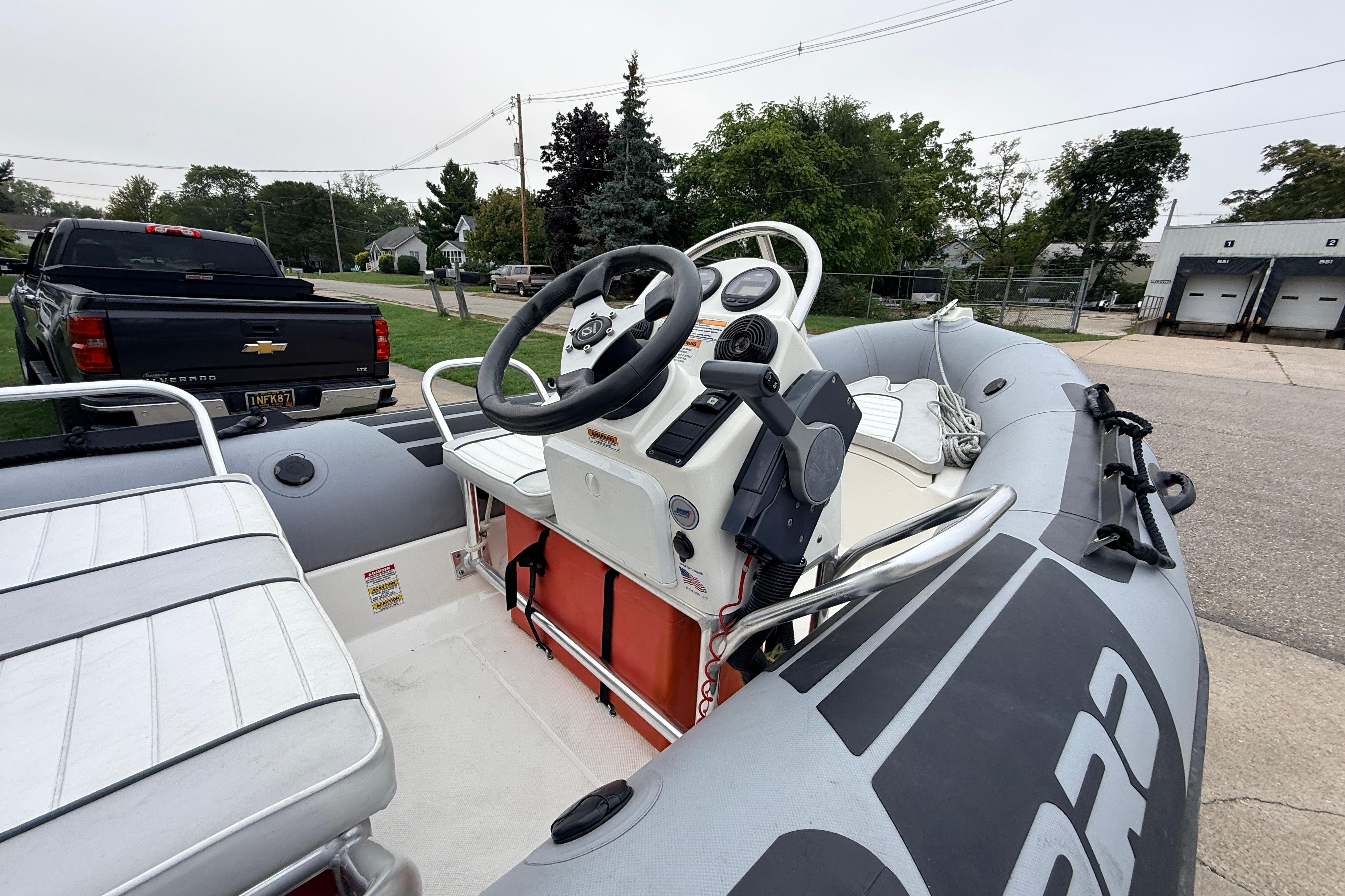2014 Zodiac Pro Classic 420 inflatable boat with steering console, parked near a black Chevrolet truck.
