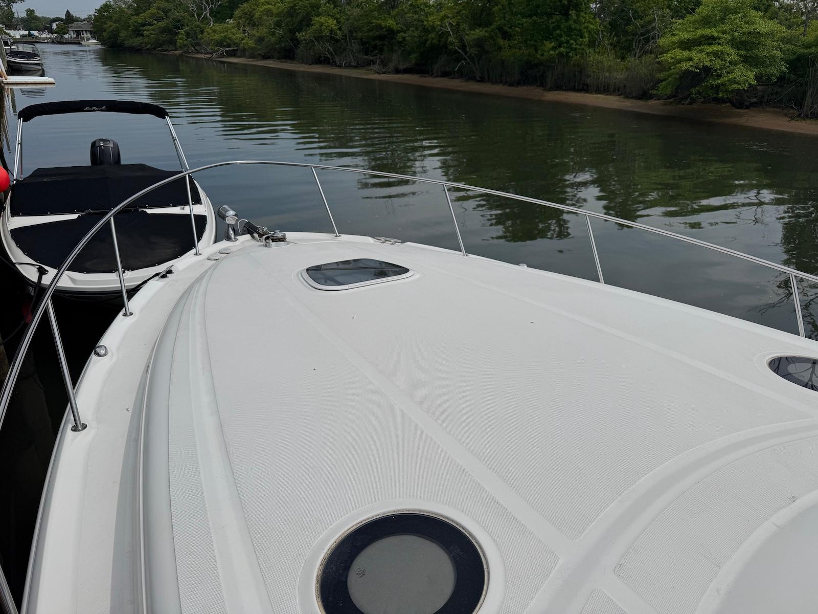 2003 Sea Ray 340 Sundancer yacht on calm river, surrounded by lush greenery.