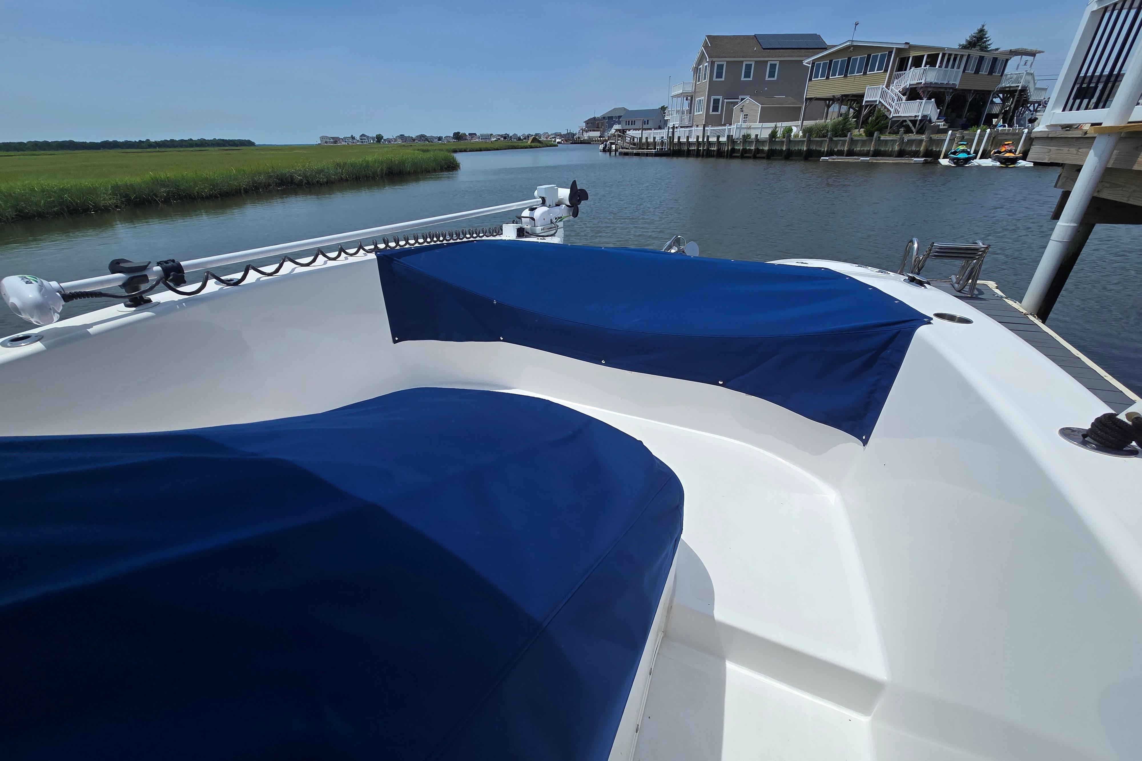 2021 Twin Vee 280 GFX CC boat with blue covers docked by waterfront homes.