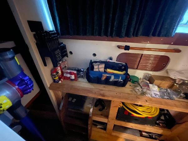 Interior of a 1951 Chris-Craft Catalina boat with tools and supplies on a wooden shelf.