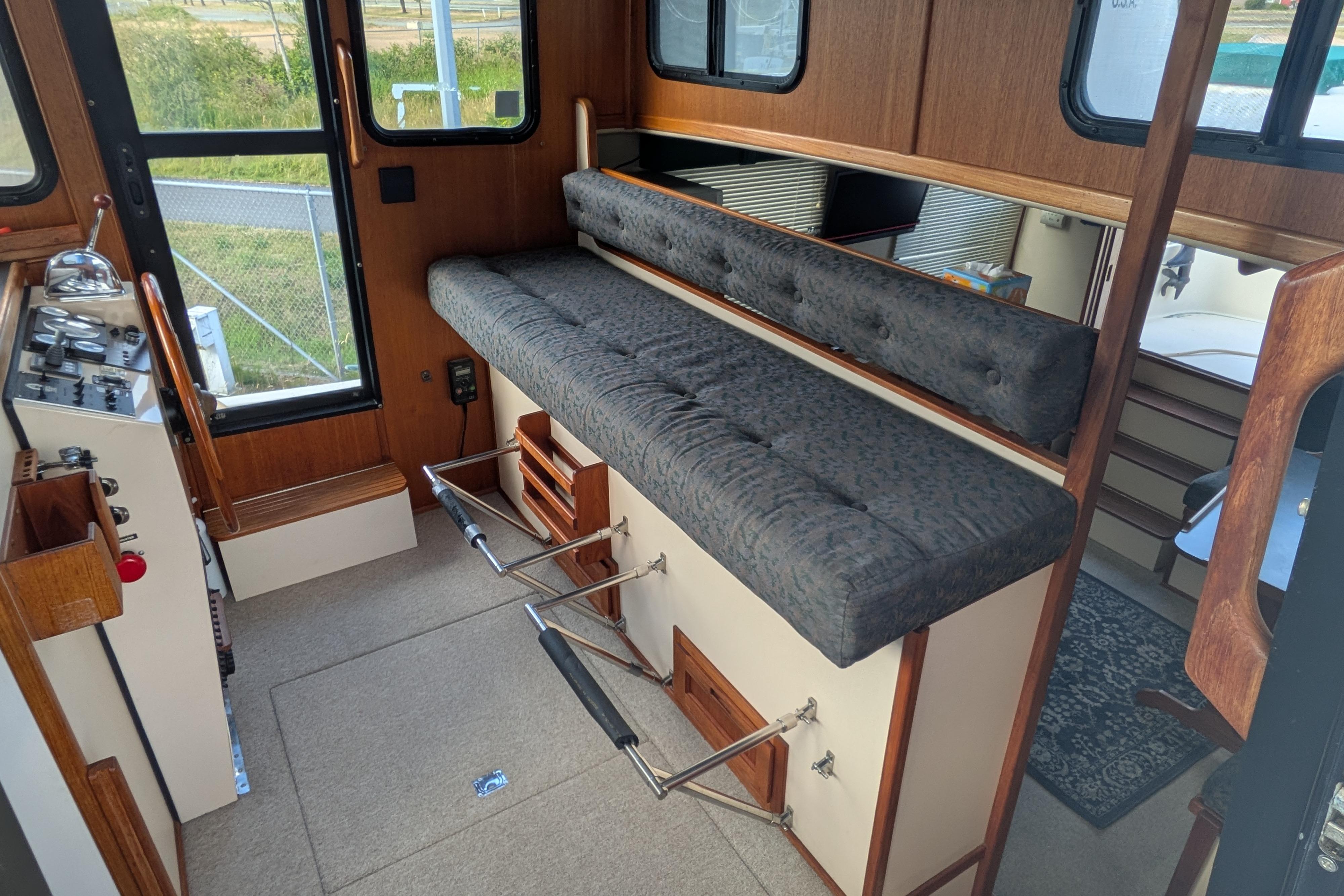 Interior of a 1998 Nordic Tug 32, featuring a cozy seating area and control panel.