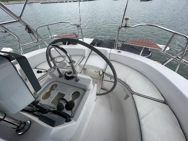 The cockpit of a 2000 Hunter 410 with steering wheel and instruments, situated on calm water.