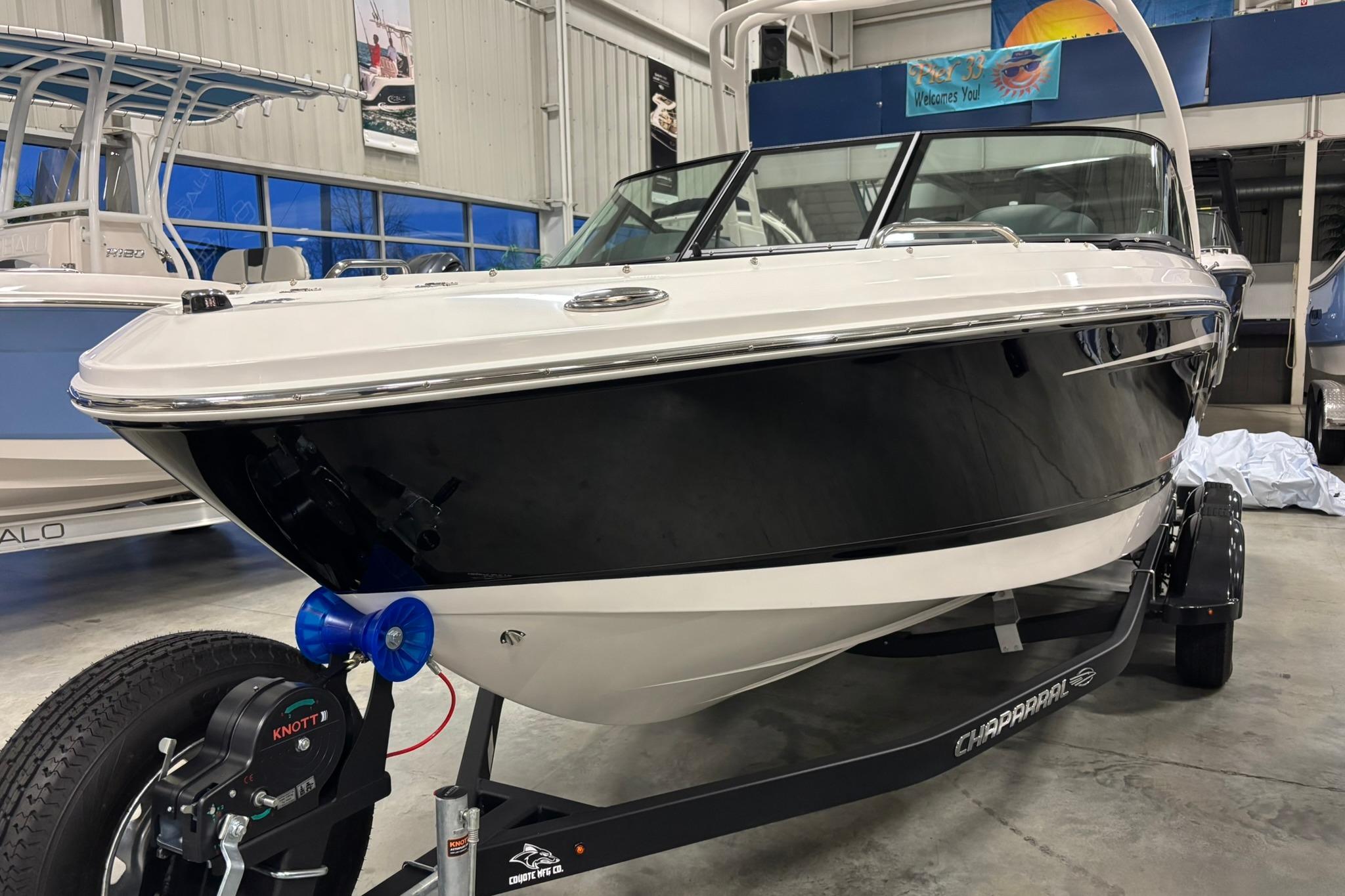 2026 Chaparral 21 SSi OB boat in showroom, black and white design on trailer.