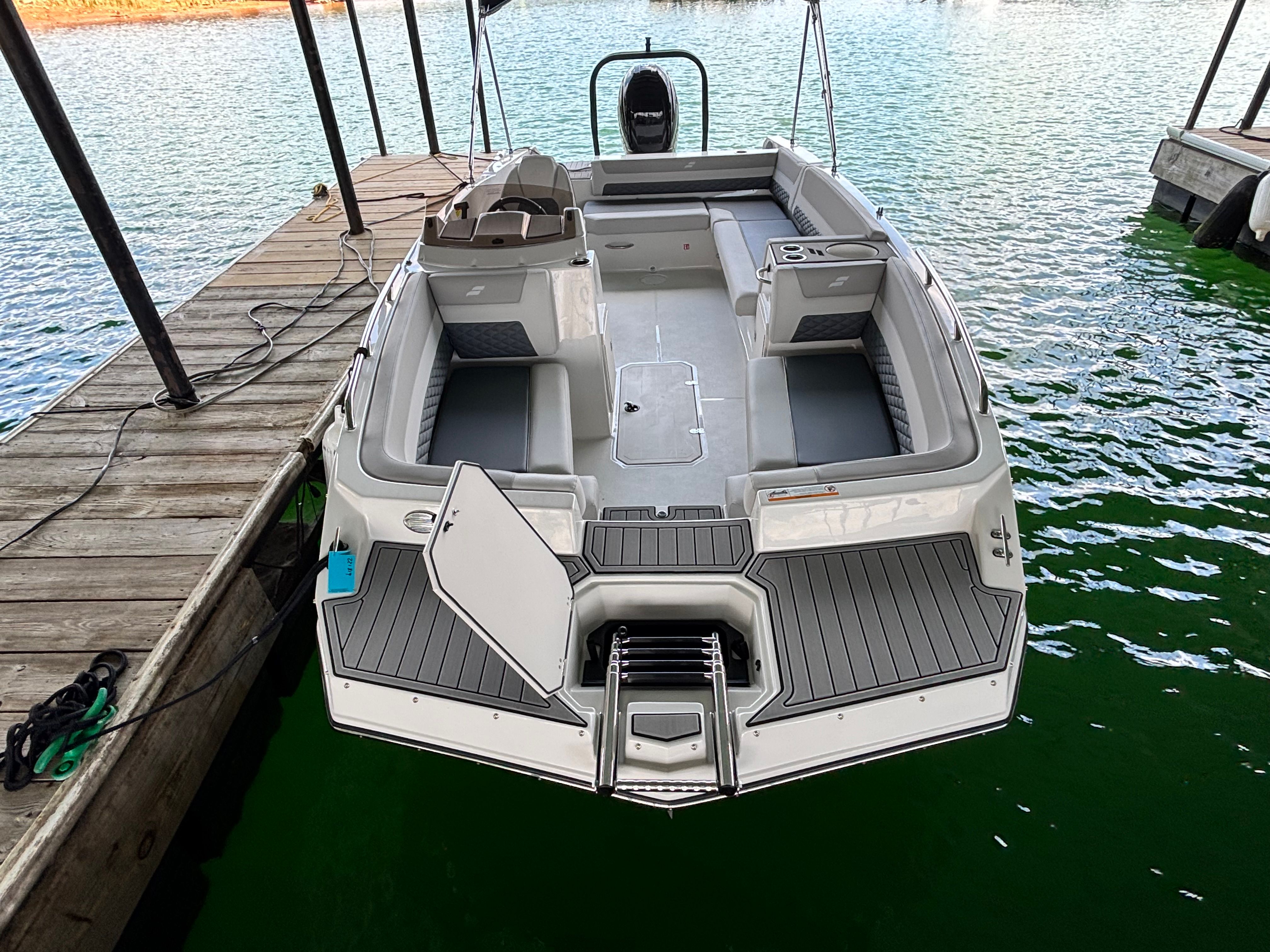 A modern 2027 Starcraft 211SVXOB docked. It features a spacious, open deck.