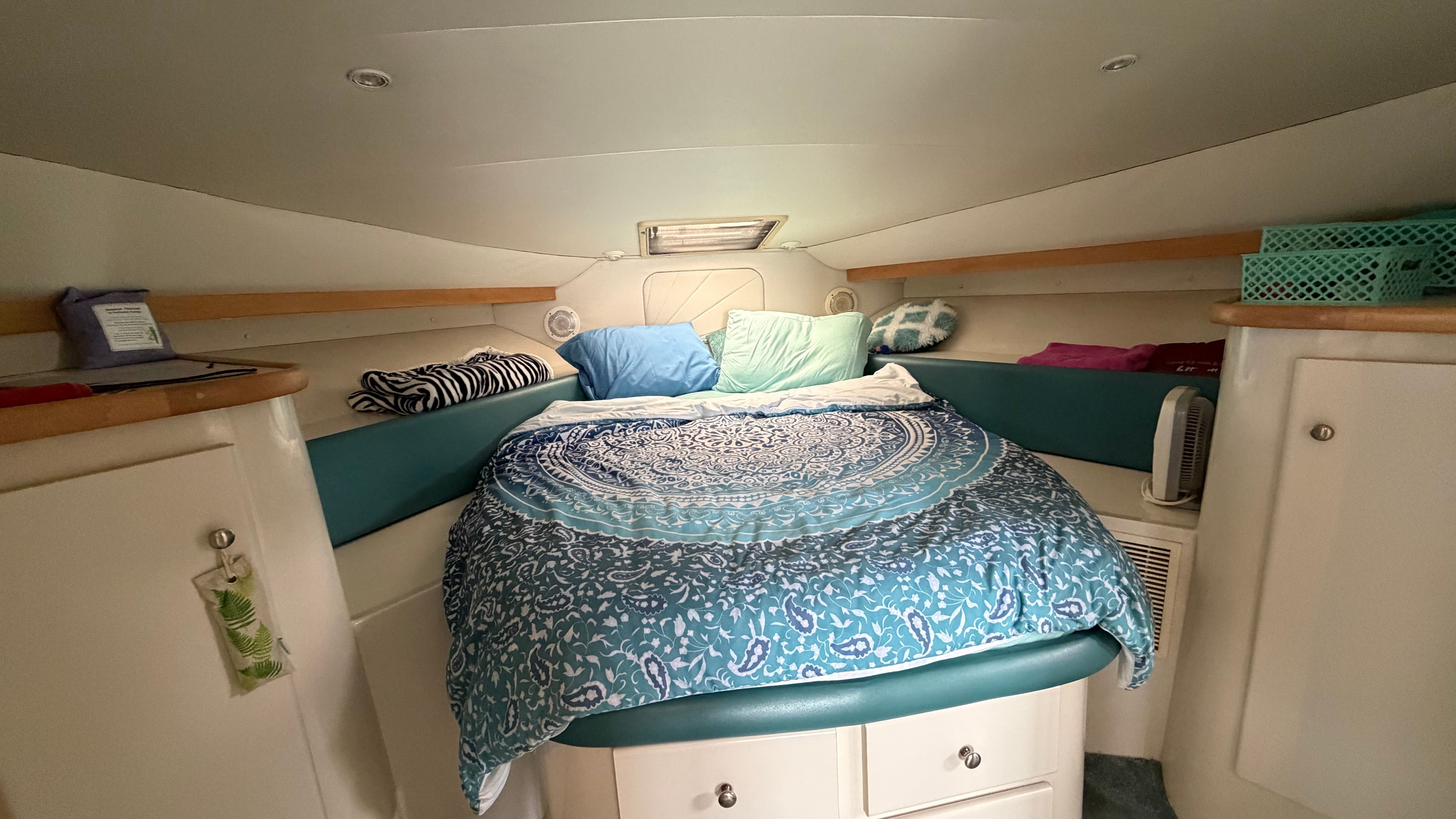 The image shows a cozy cabin with a large bed, surrounded by cabinets and shelves.