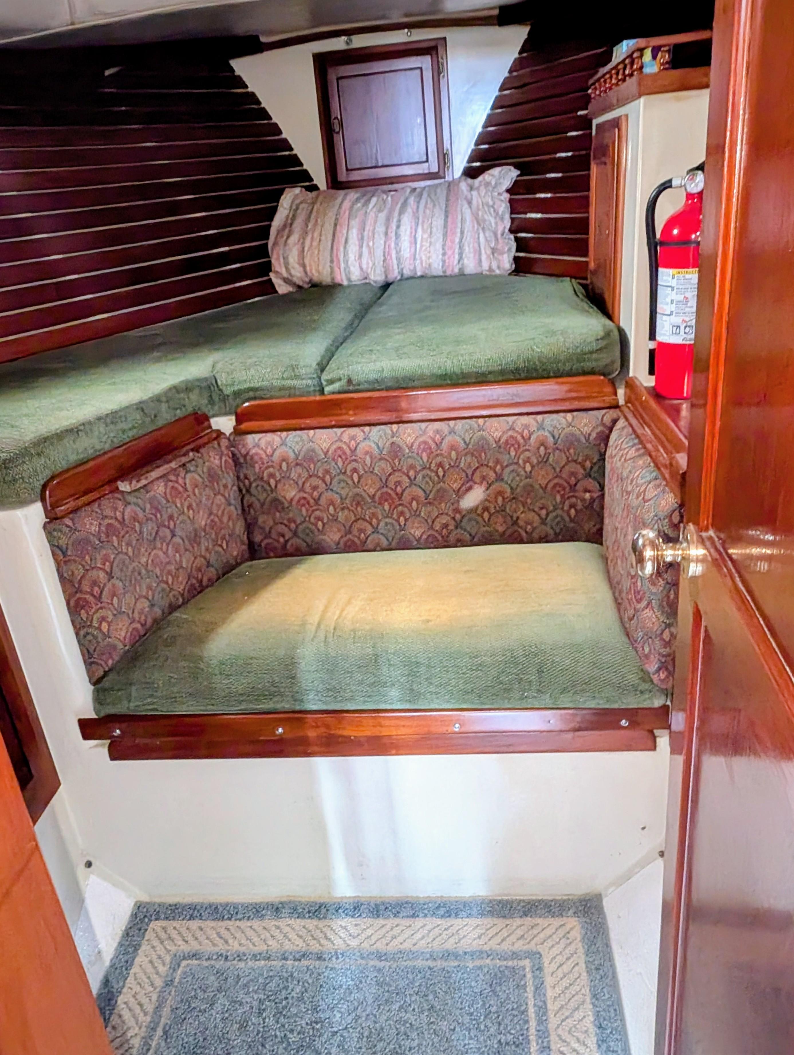 1975 Downeast Ketch interior with cozy seating, wooden accents, and a fire extinguisher.