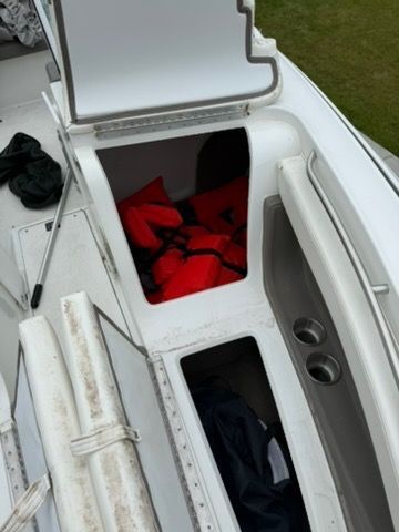 An open storage compartment on a boat with red life jackets.