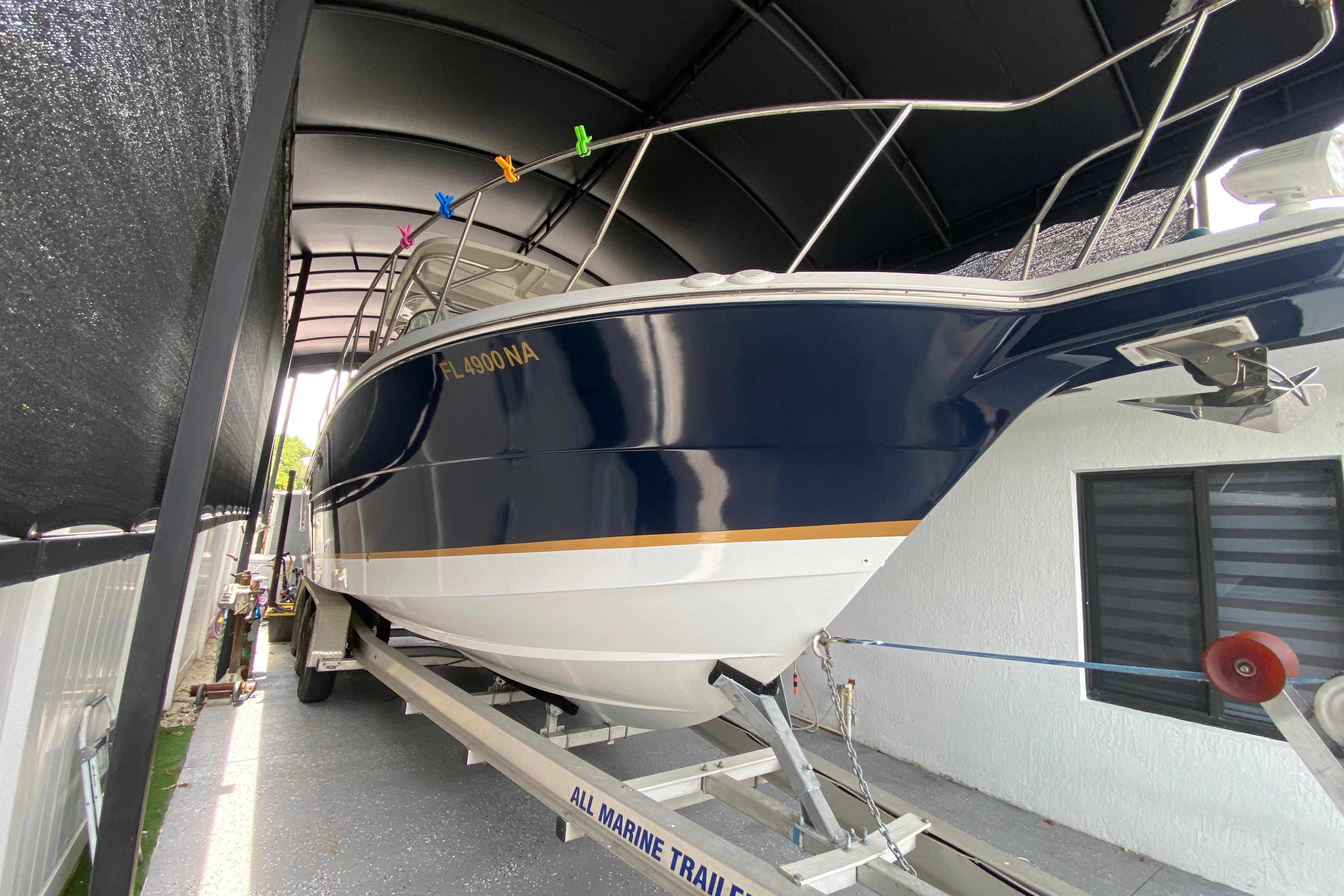 2005 Wellcraft 290 Coastal boat on trailer under a canopy, side view.
