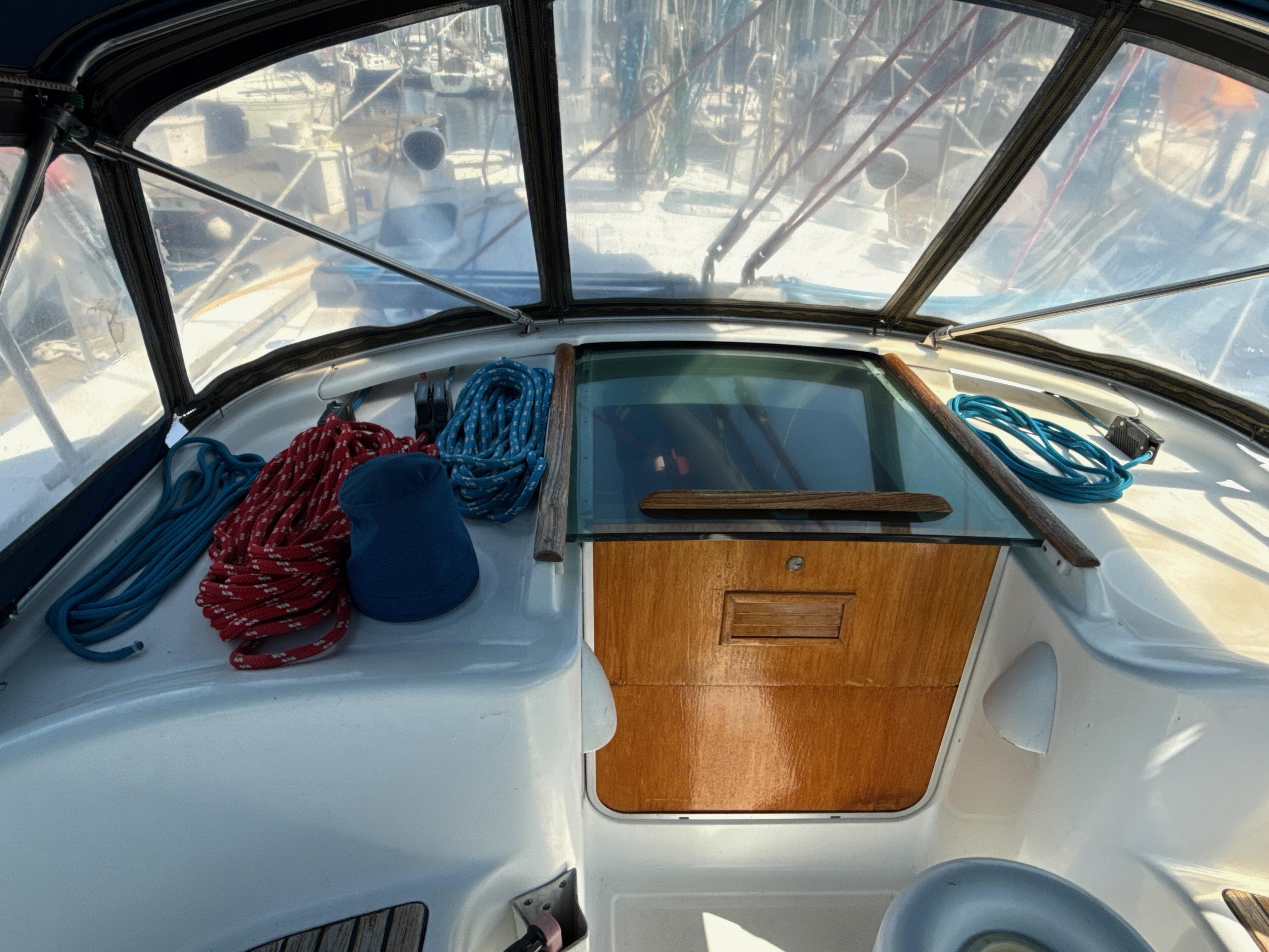 Cockpit of 1997 Beneteau 50 sailboat with ropes and wooden hatch.
