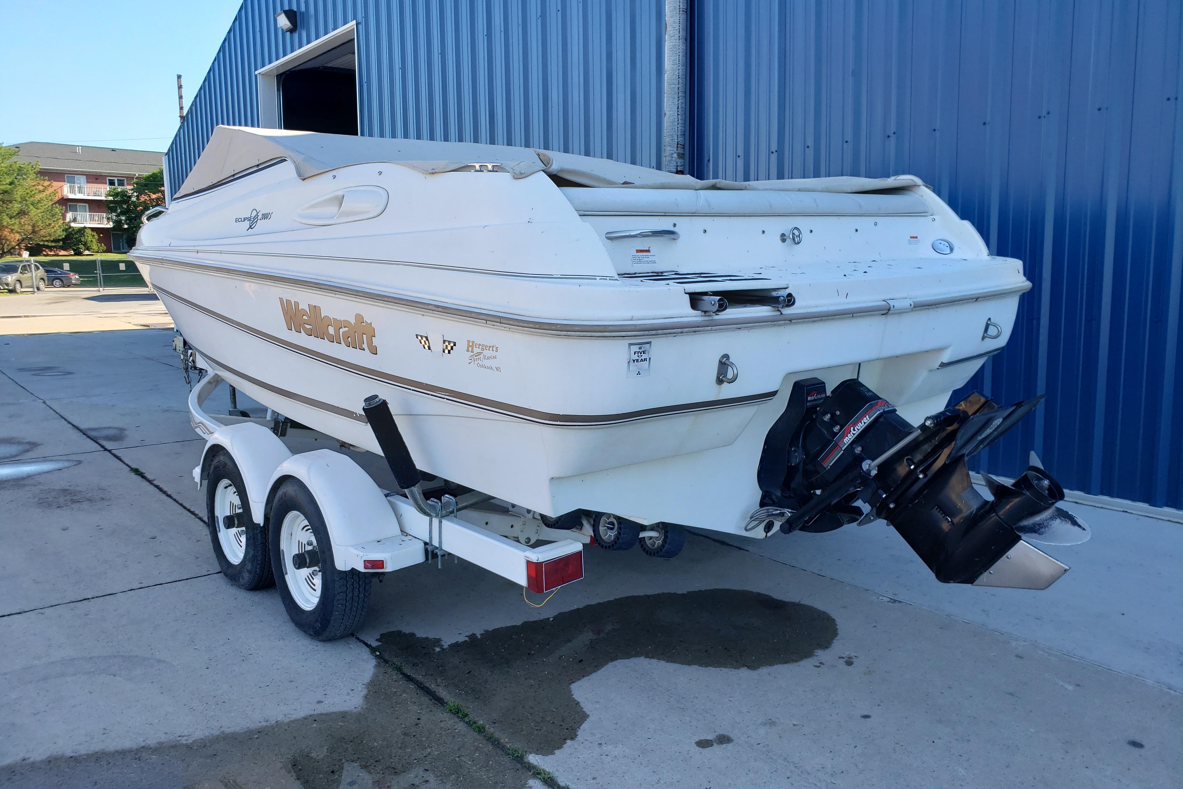 1998 Wellcraft Eclipse 2000 SS boat on trailer, parked near blue building.