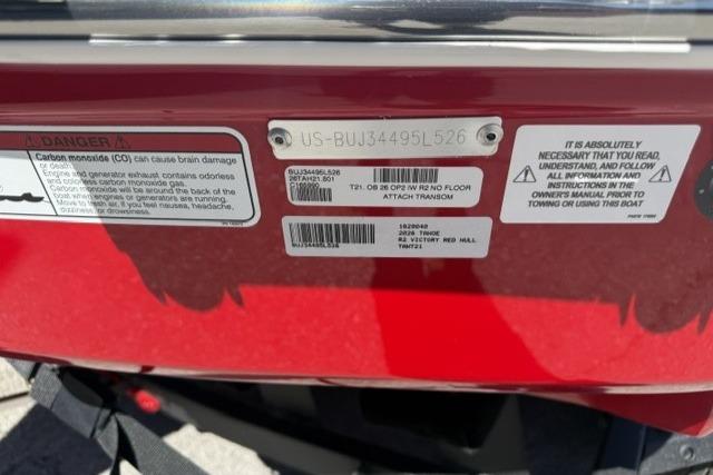 2026 Tahoe T21 boat warning labels and identification plate on red surface.