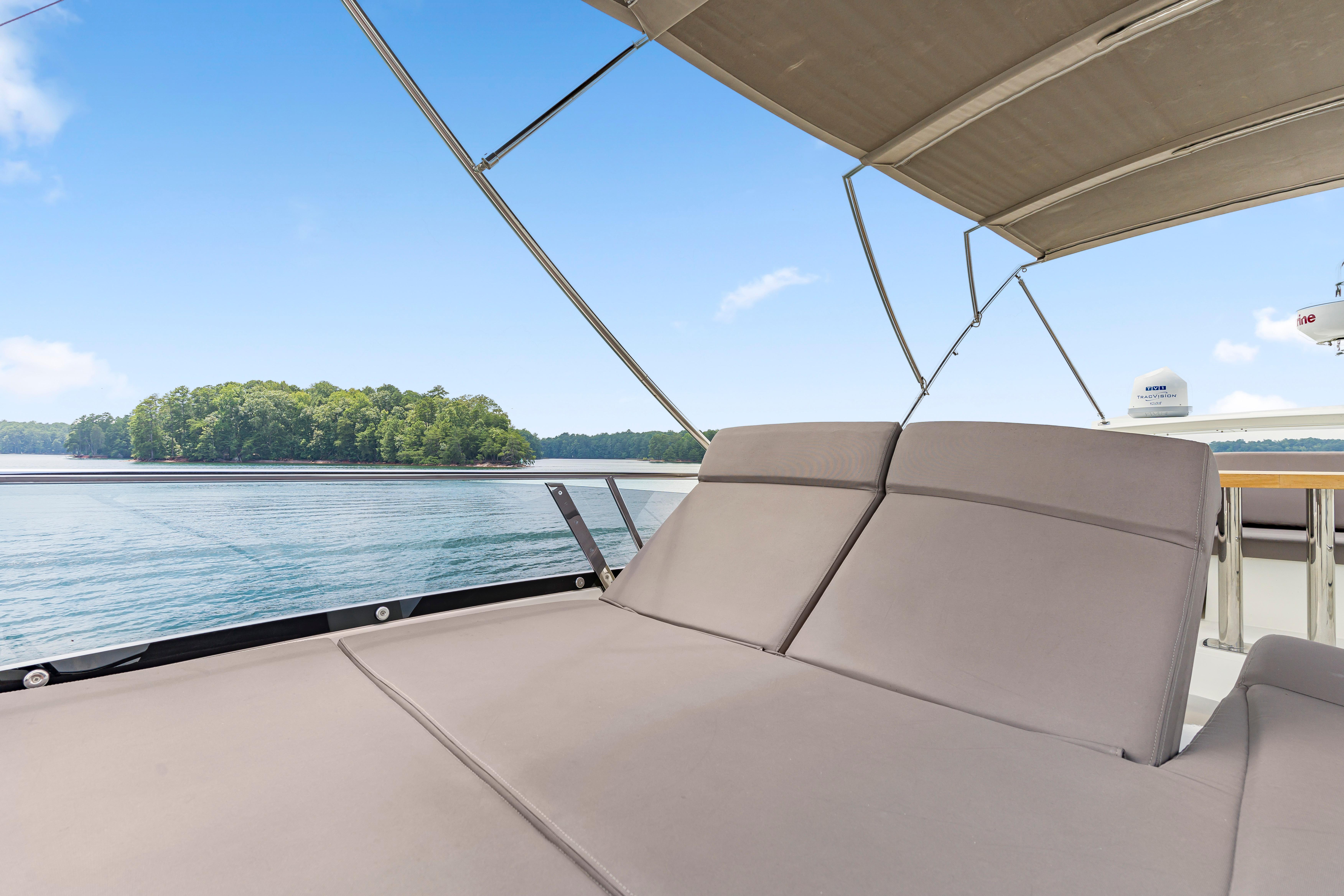 Luxurious 2017 Prestige 500 yacht with sunbed, overlooking serene water and lush island.