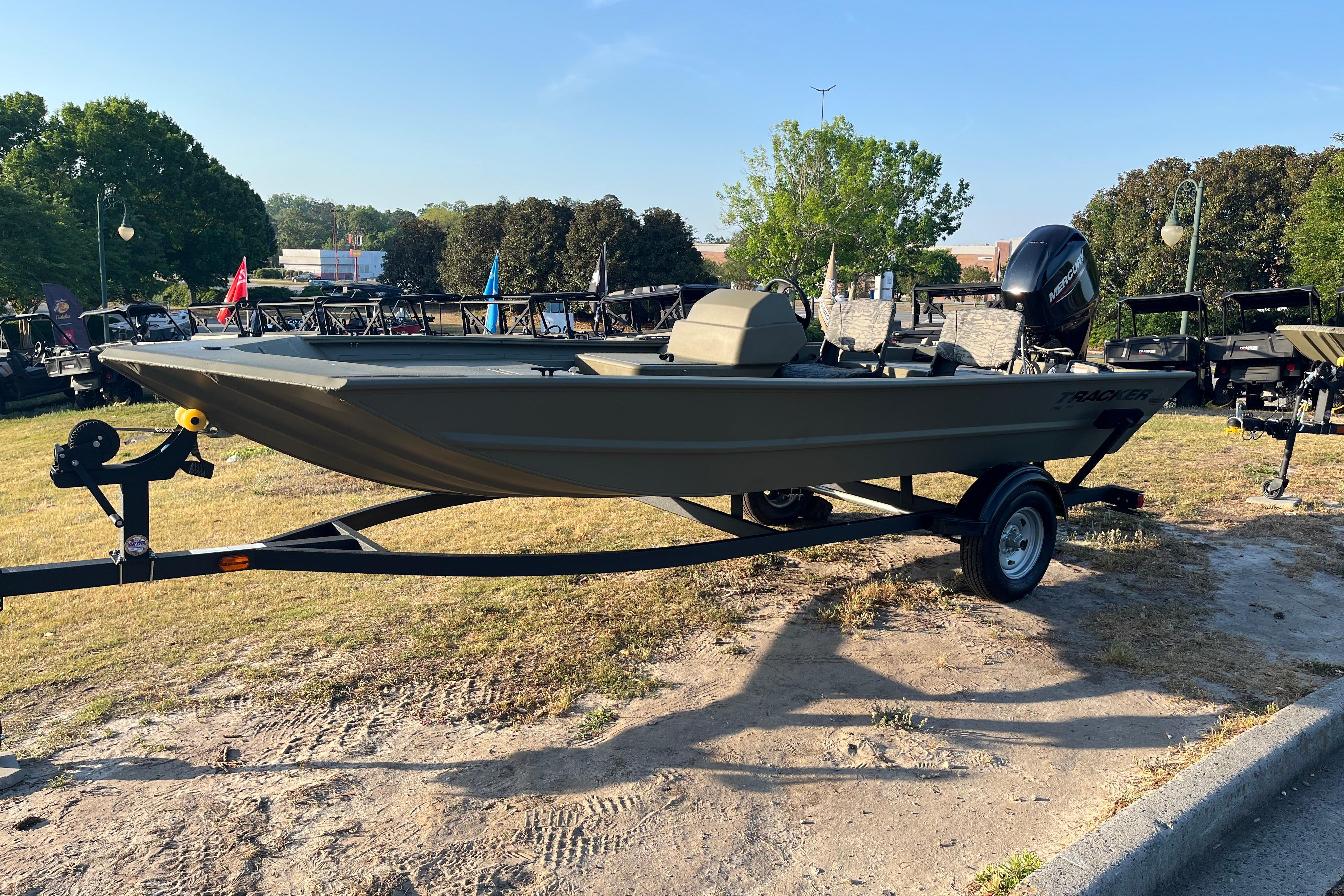 2026 Tracker Grizzly 1754 SC boat on trailer, parked outdoors in a grassy area.