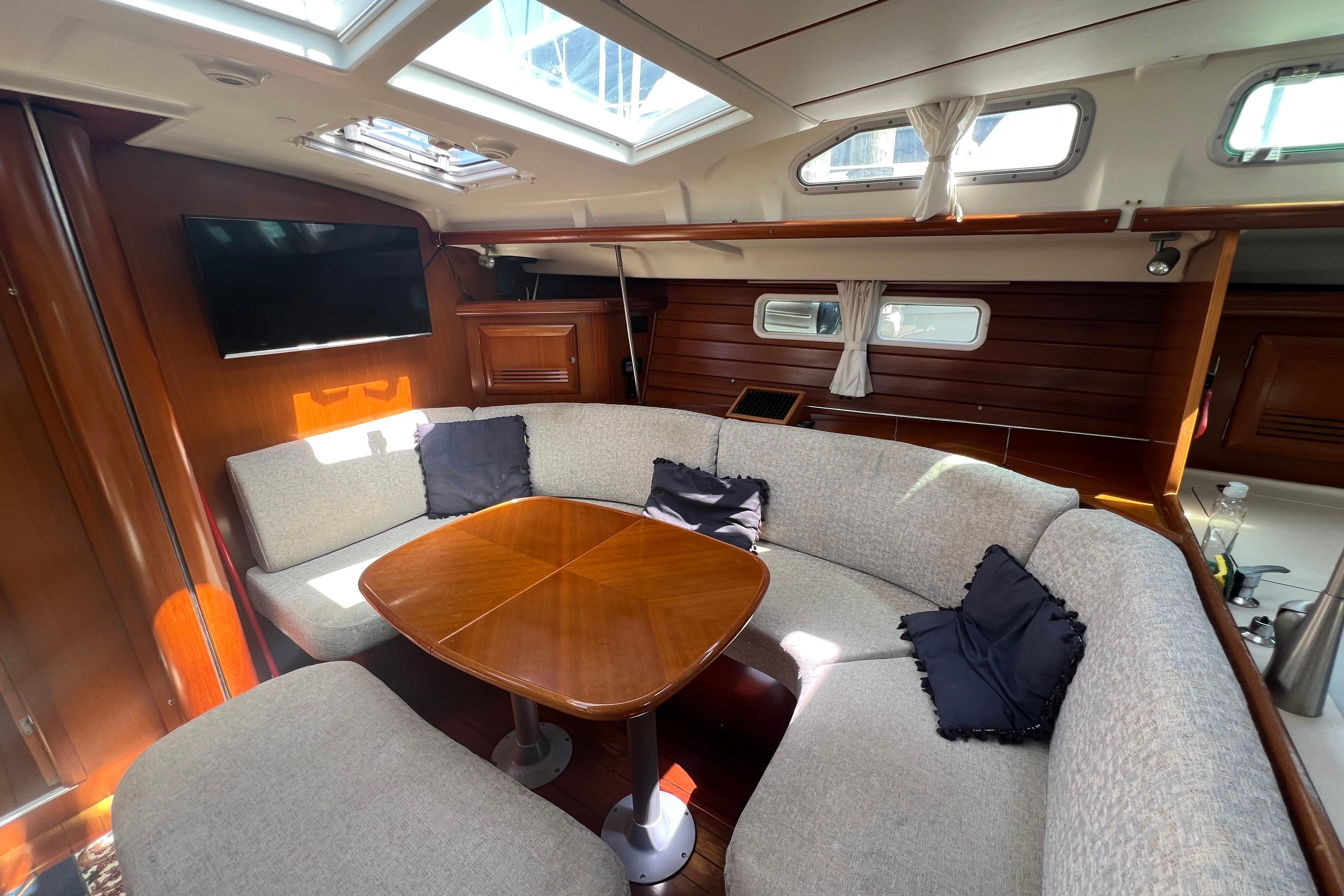Interior of 2001 Beneteau Oceanis 473 yacht with cozy seating and wooden table.