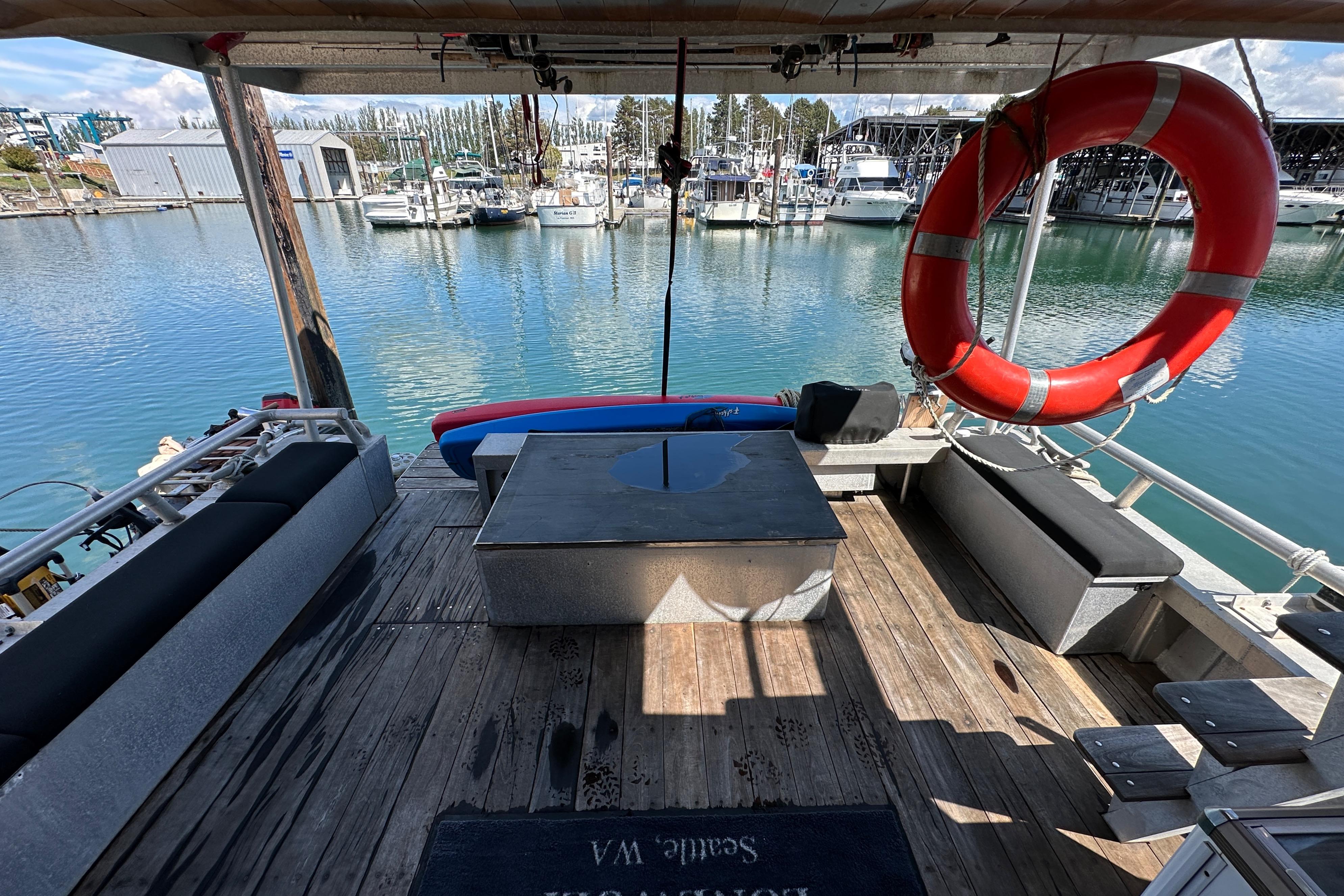 Deck of 2002 Carlson Marine Trawler with seating, life preserver, and marina view.